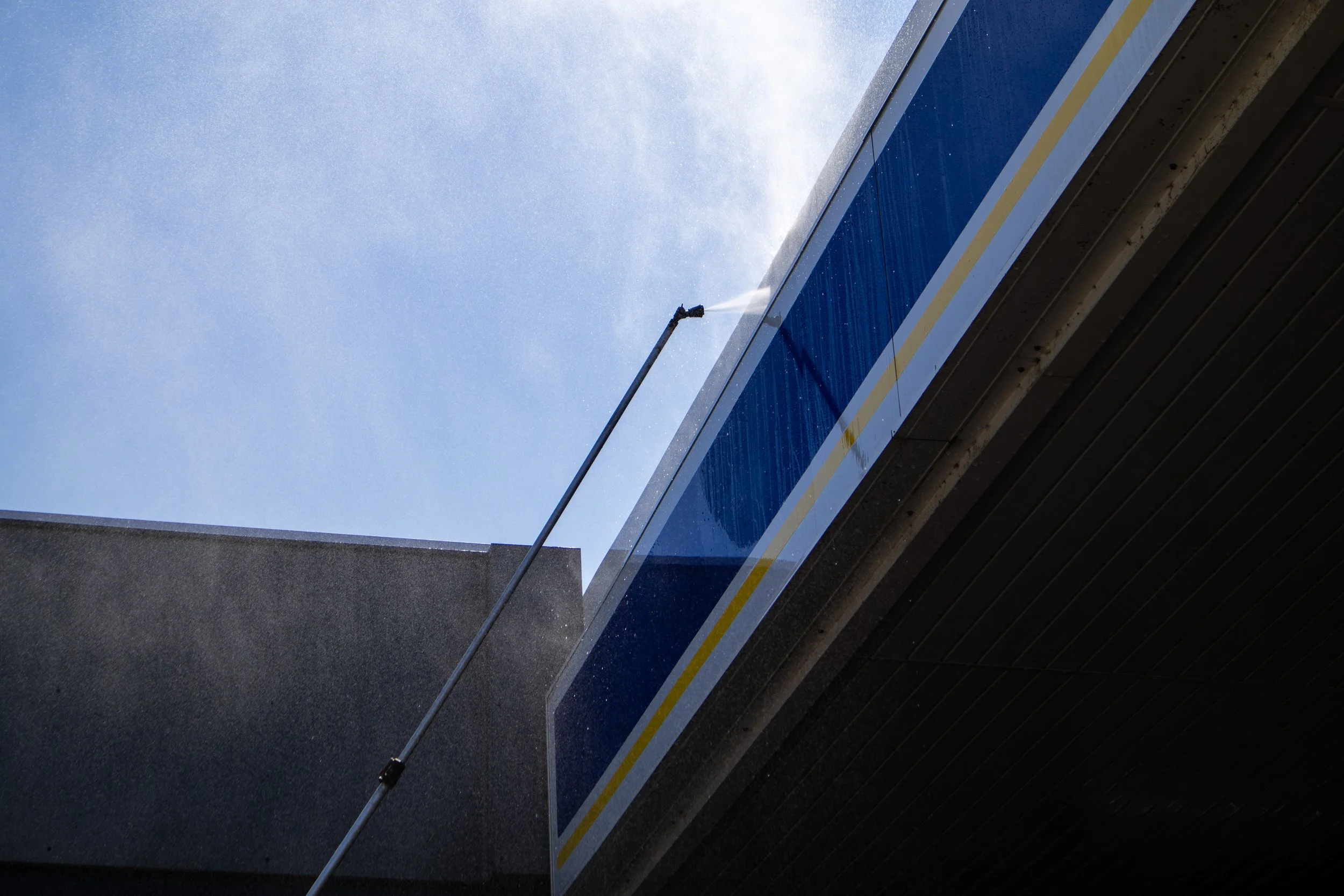 Een gebouw met een blauwe gevel en een raam die wordt schoongemaakt met een hoge drukreiniger.