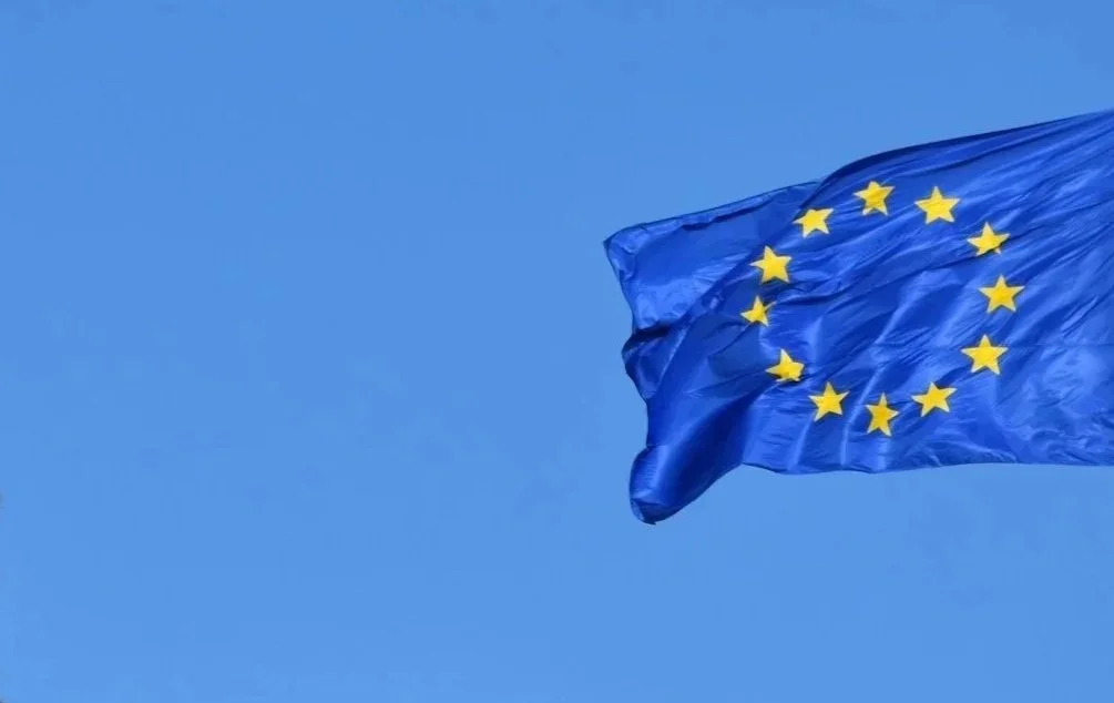 Bandera de la Unión Europea ondeando en el cielo azul.