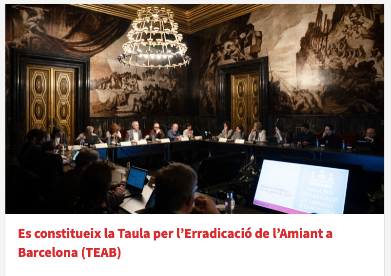Reunión formal en una sala decorada con murales antiguos, con varias personas sentadas alrededor de una mesa grande, participando en una discusión o presentación.