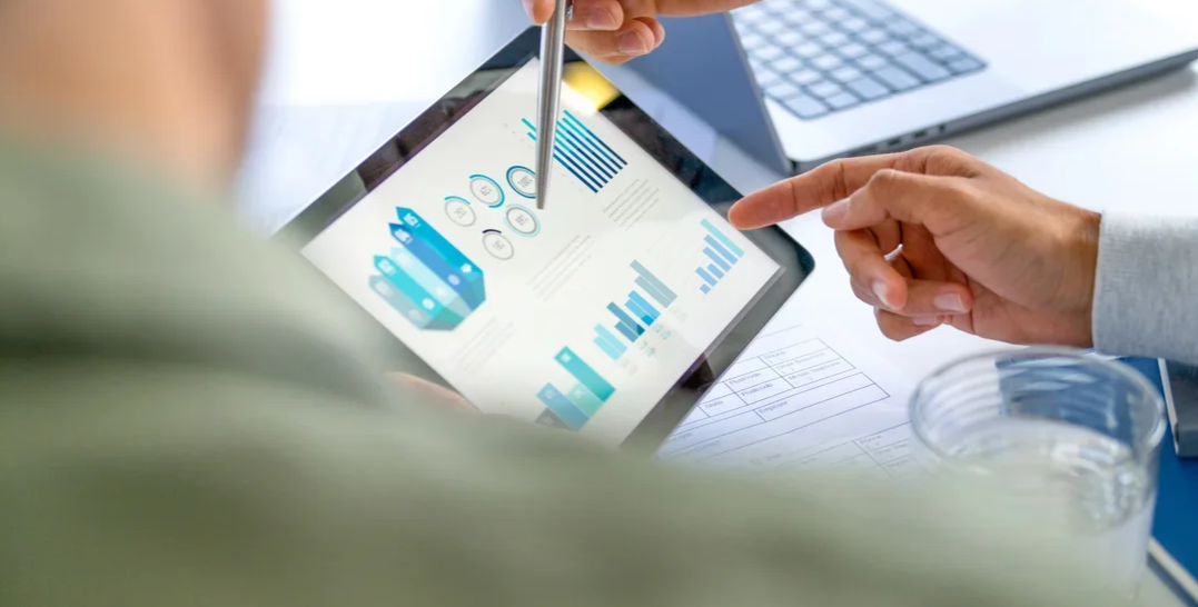 Personas trabajando con una tableta que muestra gráficos y datos en una reunión.