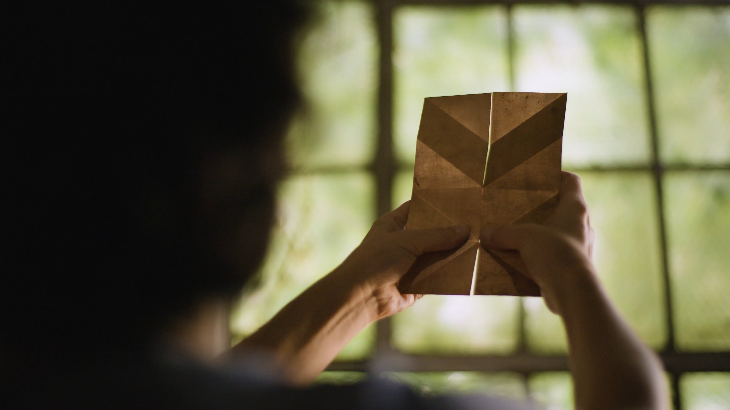 Kei Tominaga looks at two pieces of metal against the window