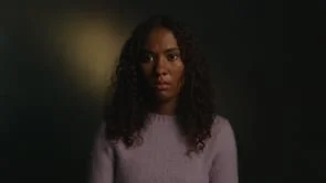 A woman has an interview in a dark setting with moody lighting