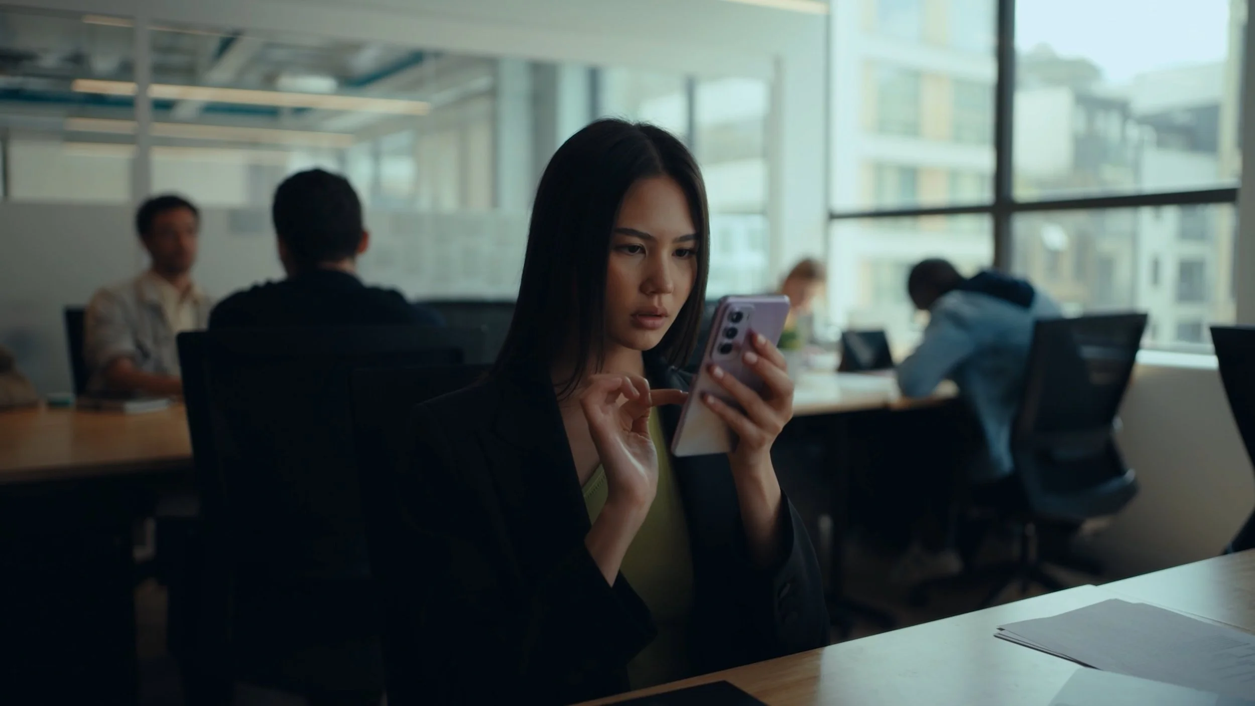 A woman looks at her OPPO Omega phone in an office