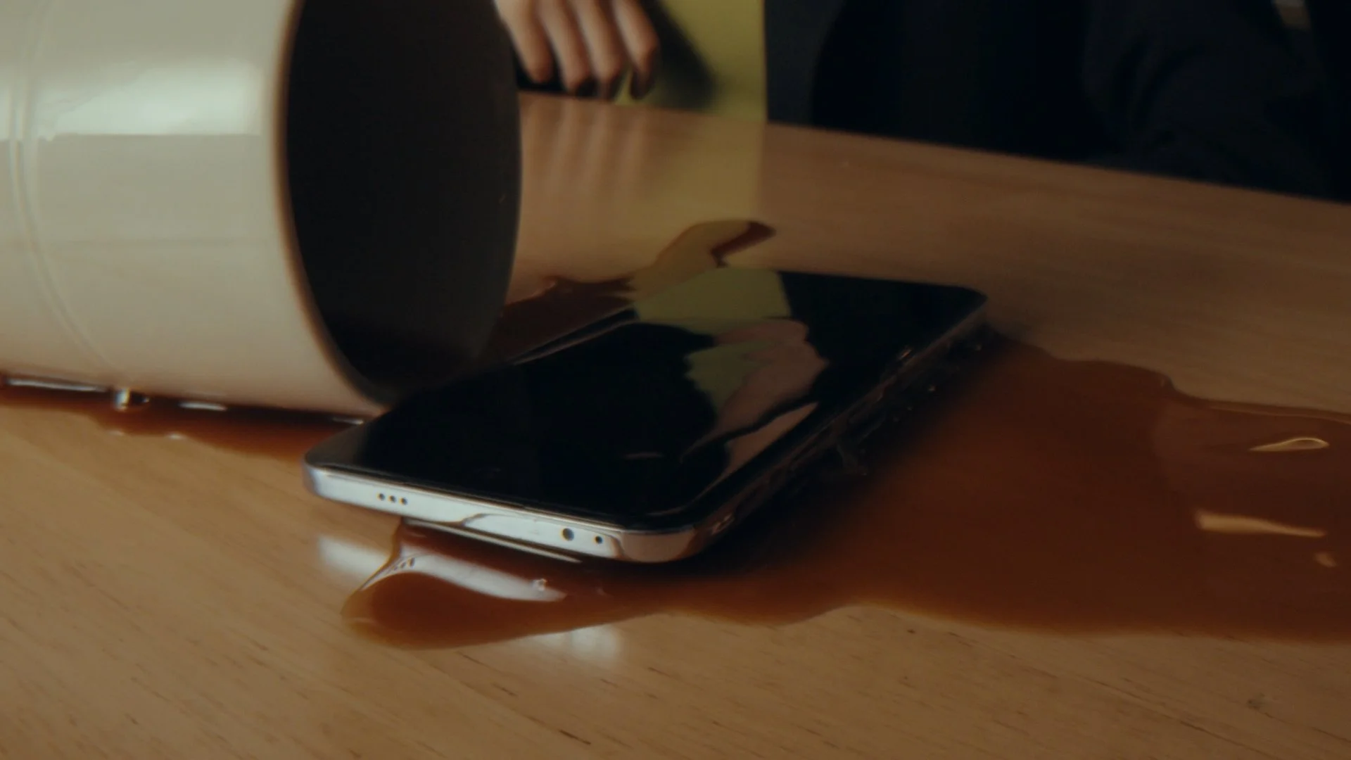 A mug of coffee spills over the OPPO Omega phone on the table
