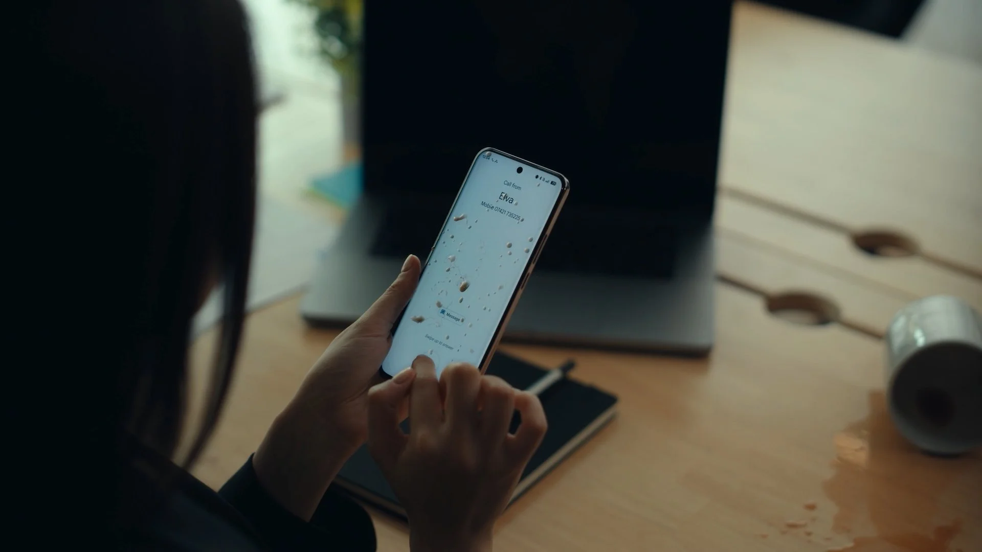 The woman holds the OPPO Omega phone while coffee still drips from it