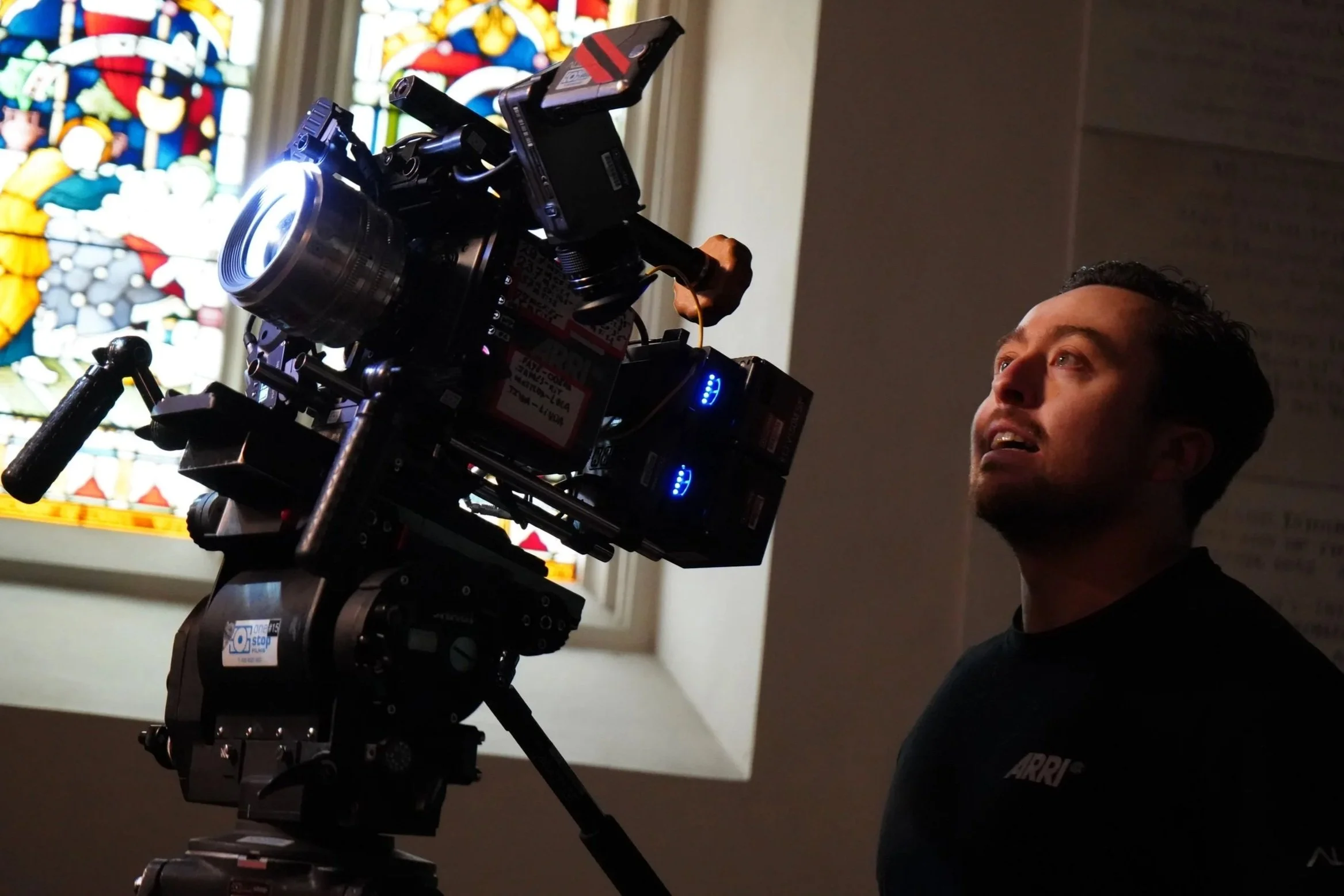 Adam Hudson views the monitor on a camera while shooting in a church