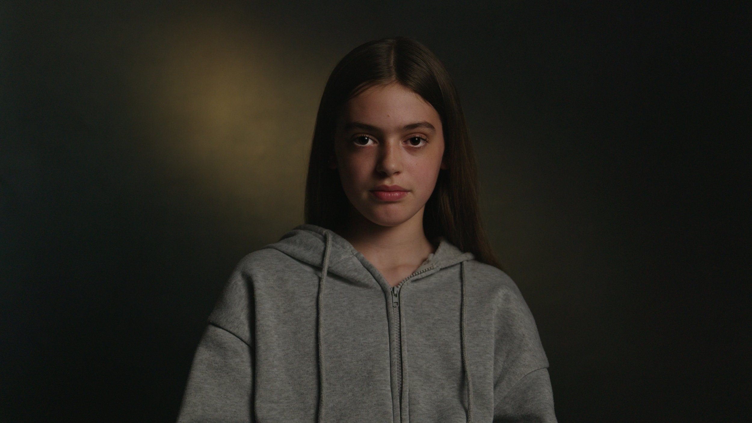 A young girl has an interview in a dark setting with moody lighting