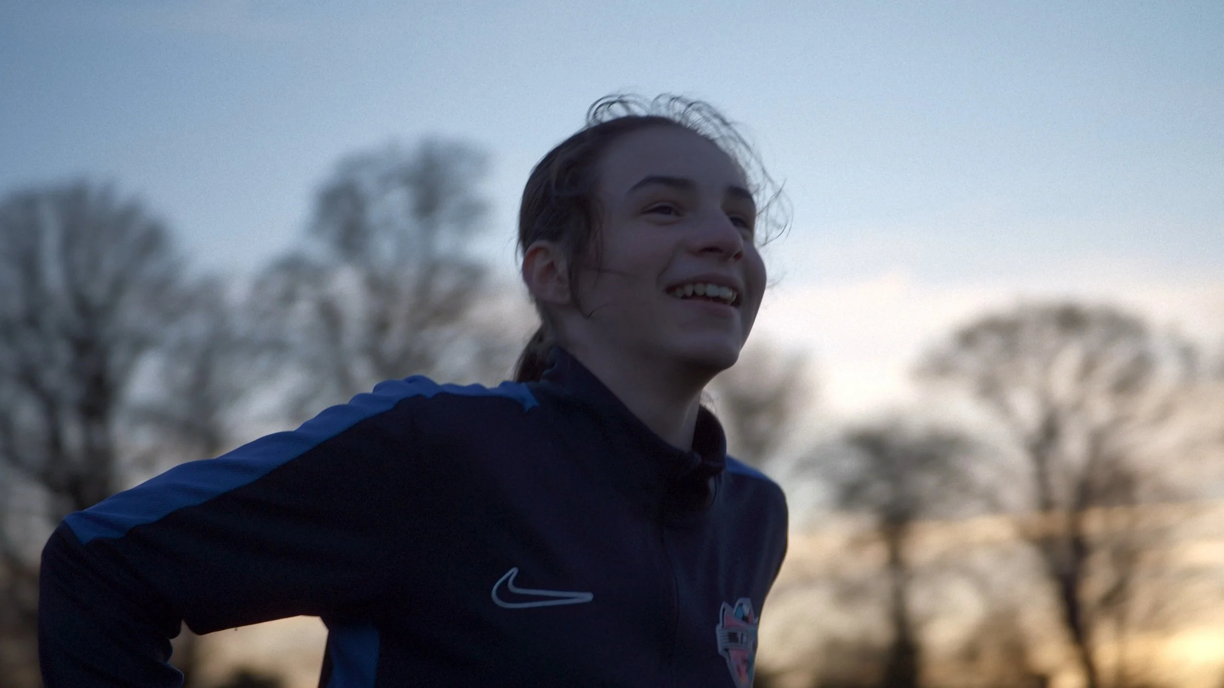 Emily smiles as she plays football at sunset