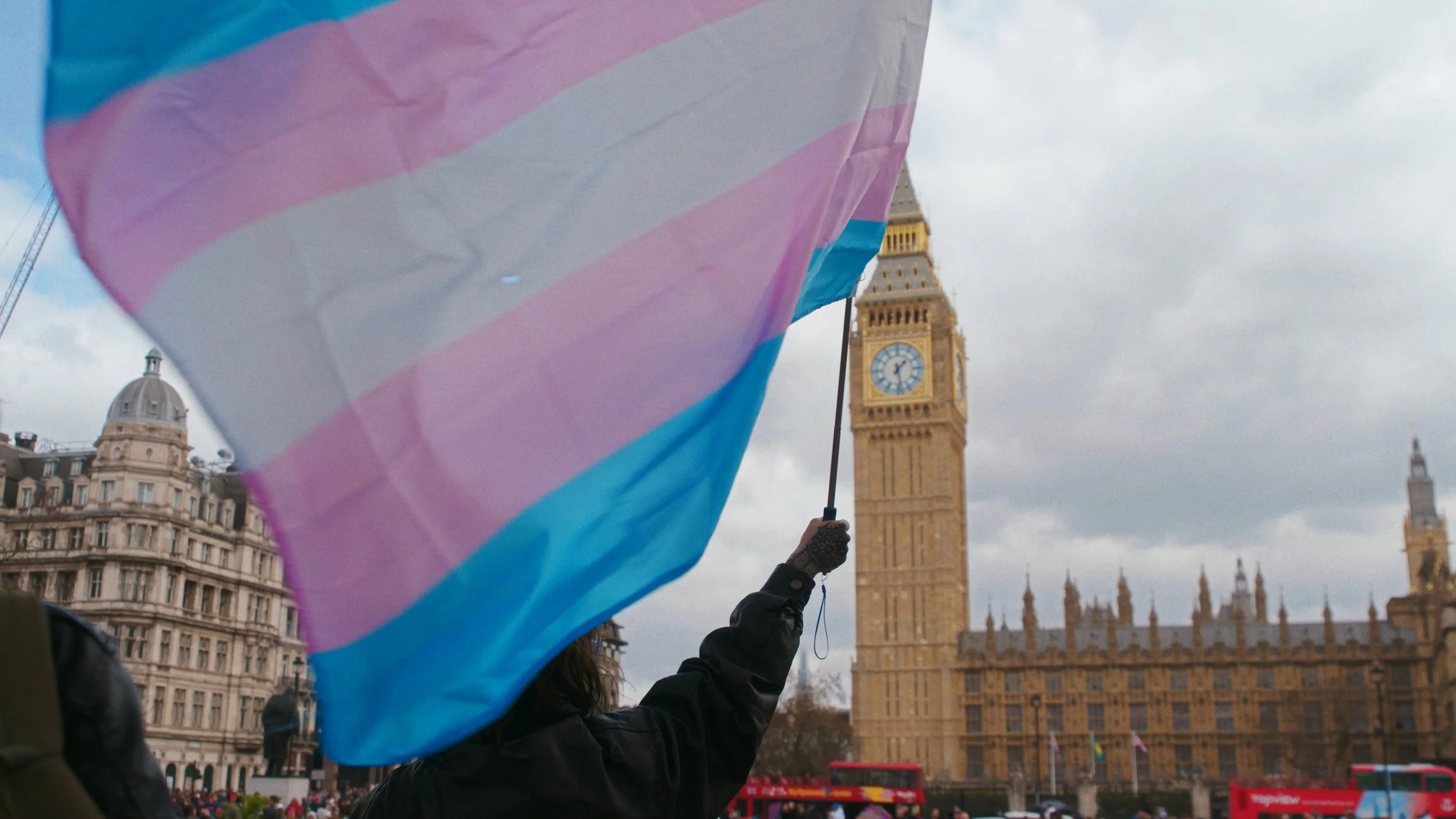 A trans flag waves as Big Ben is in the background