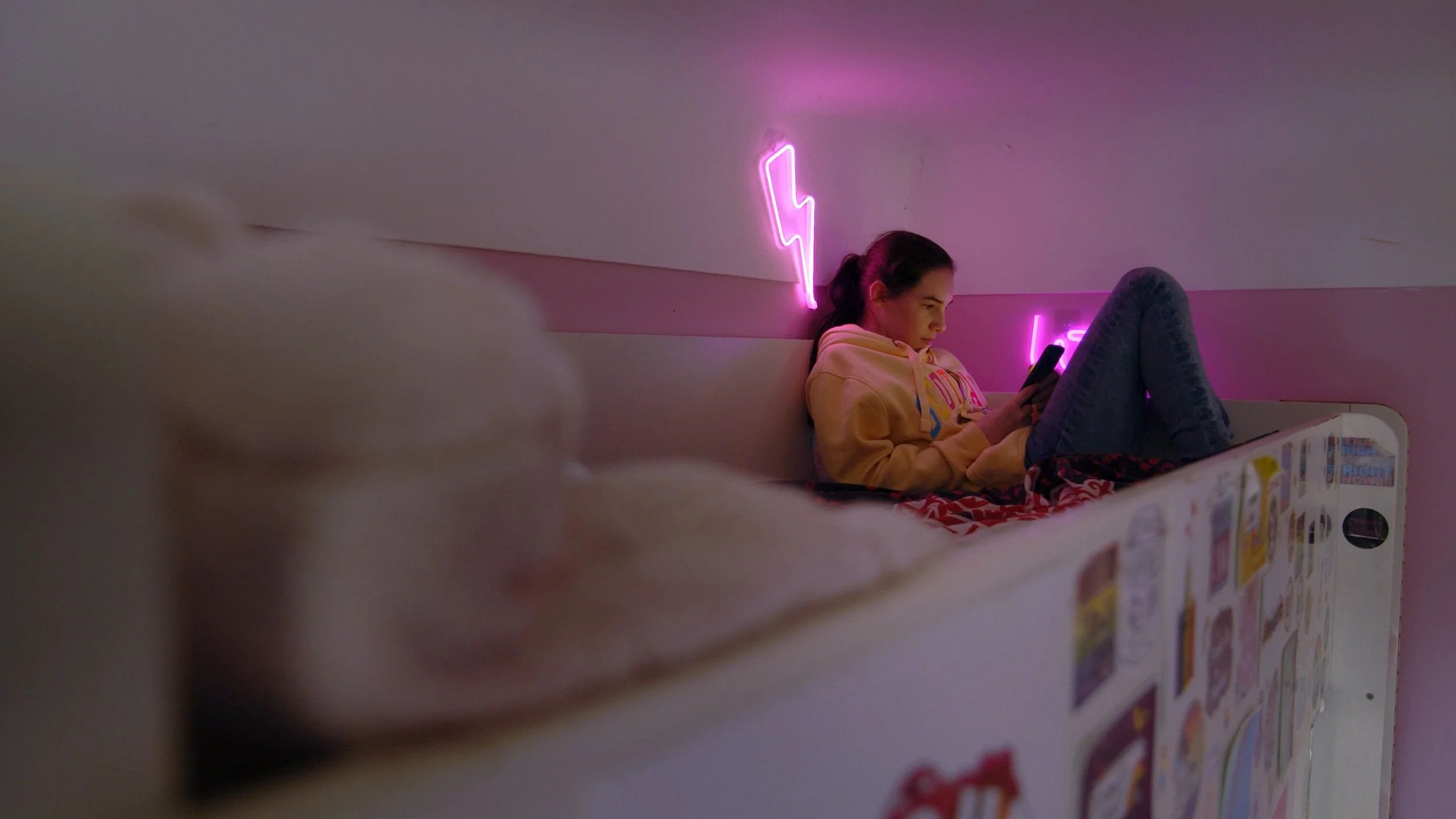 Emily sits on her bed and plays on her phone