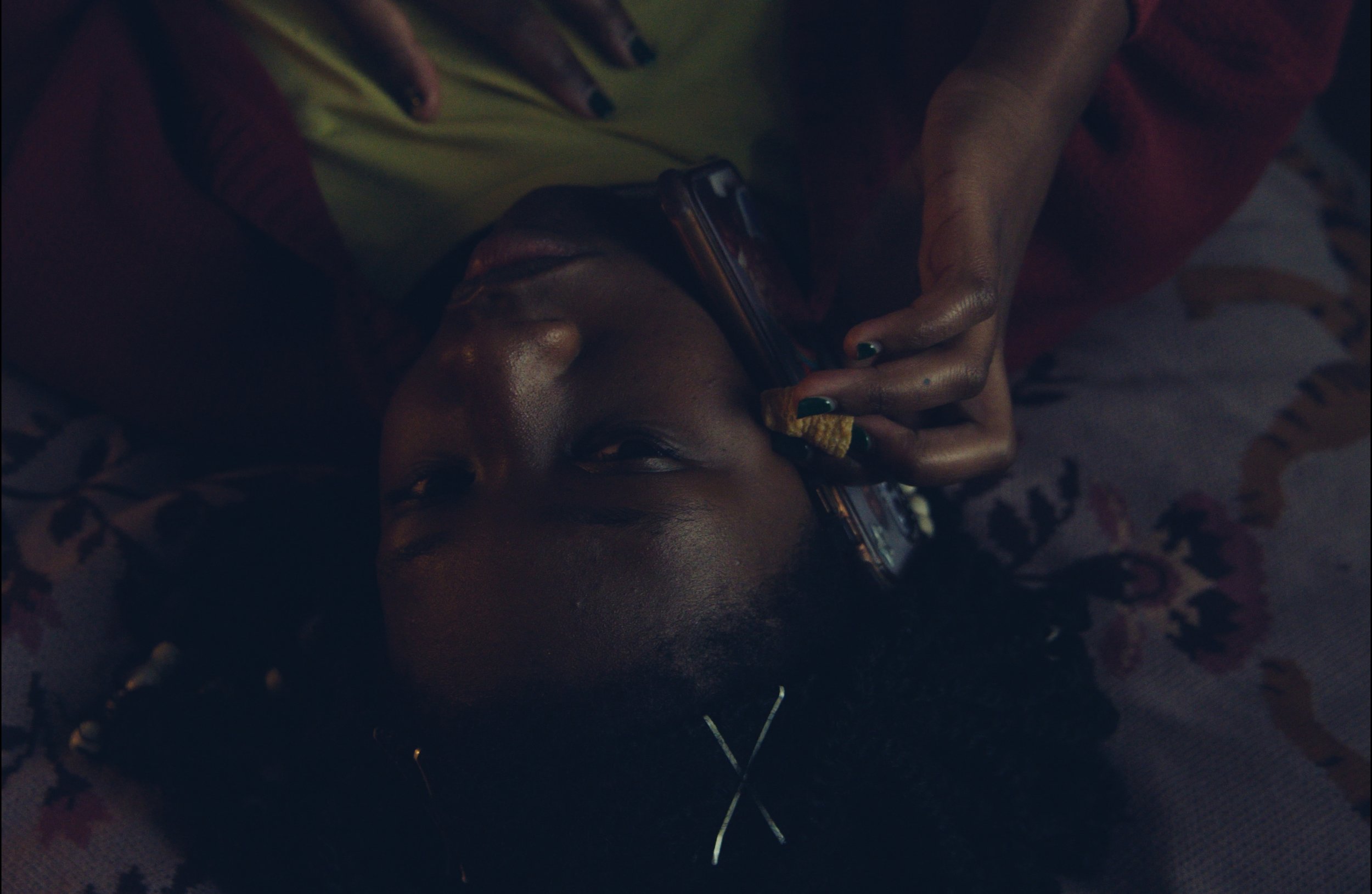 A close-up of a woman lying on her bed while she talks on the phone