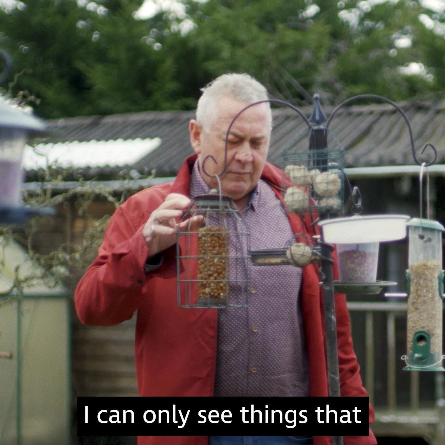 Pete in his garden filling his bird feeder, RNIB