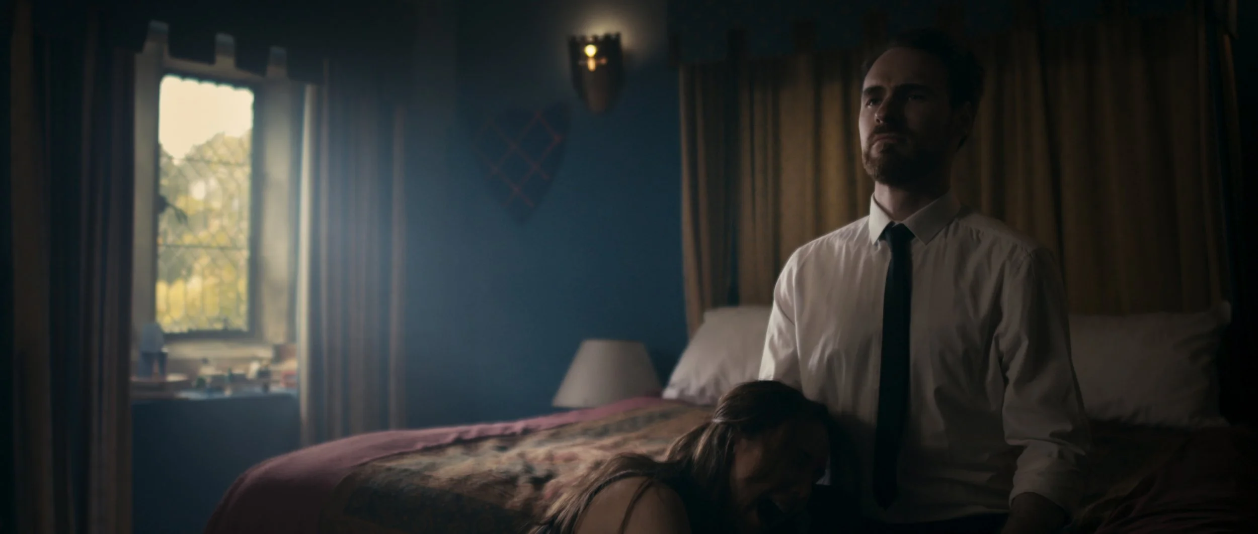 A woman cries in a man's lap in a dark room