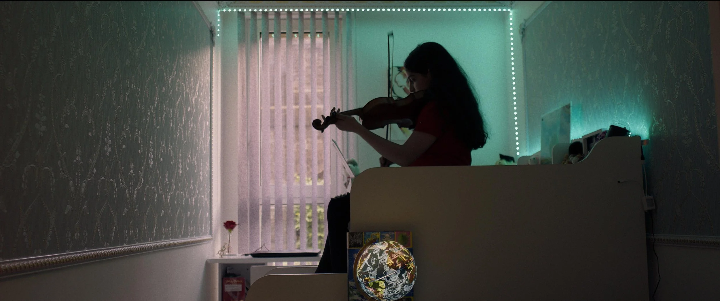 Zara plays her violin in her bedroom