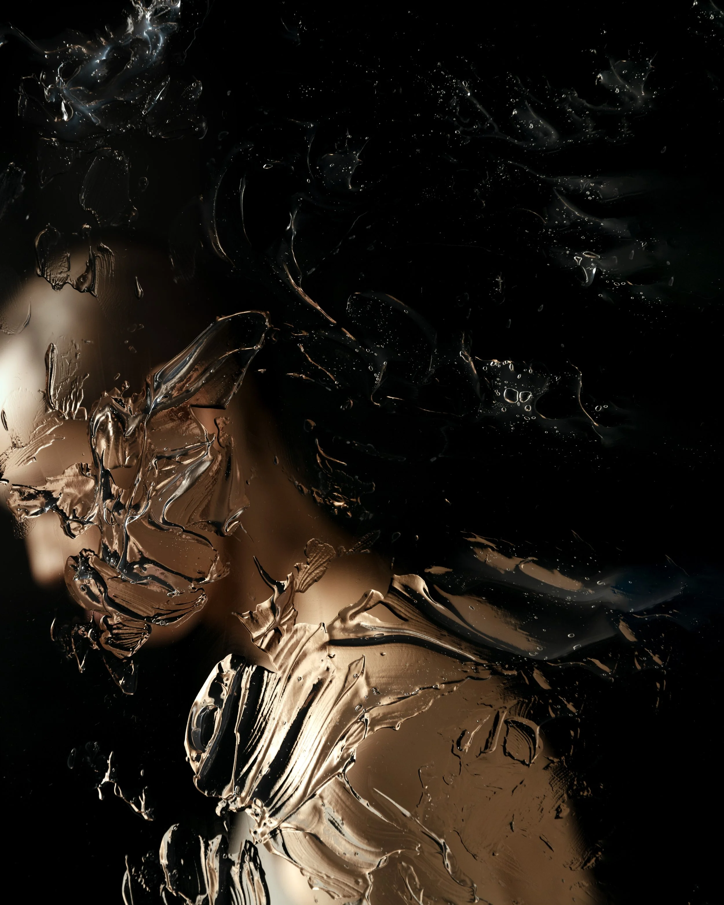 Abstract image featuring swirling, textured metallic paint in shades of beige, gray, and black against a dark background.