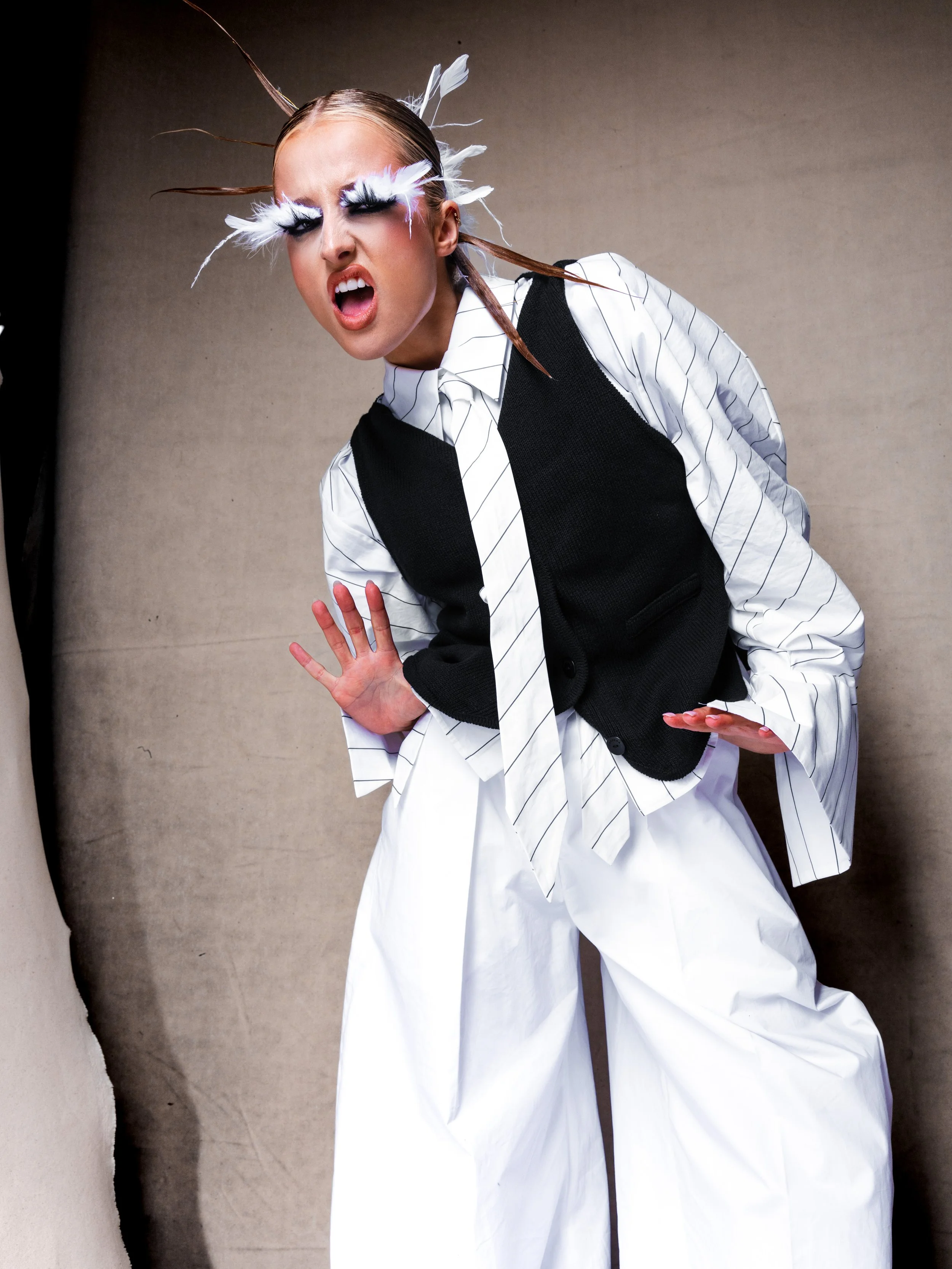 A woman with dramatic makeup and feathered eyelashes in an expressive pose.
