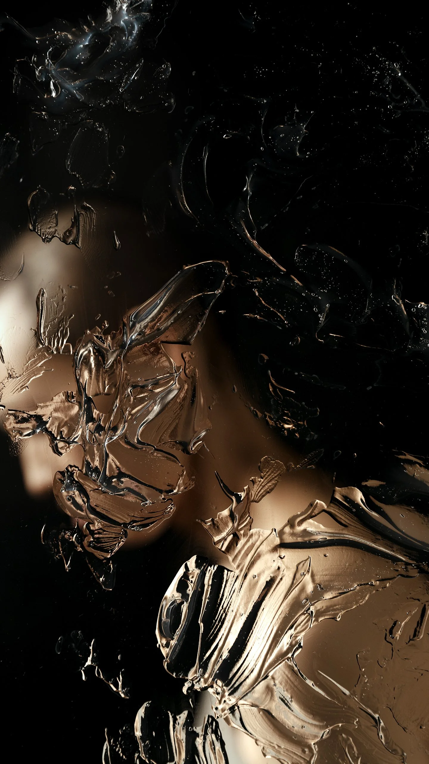 Abstract image with dark background and smudges of light brown, beige, black, and dark gray colors, resembling paint or melted metallic textures.