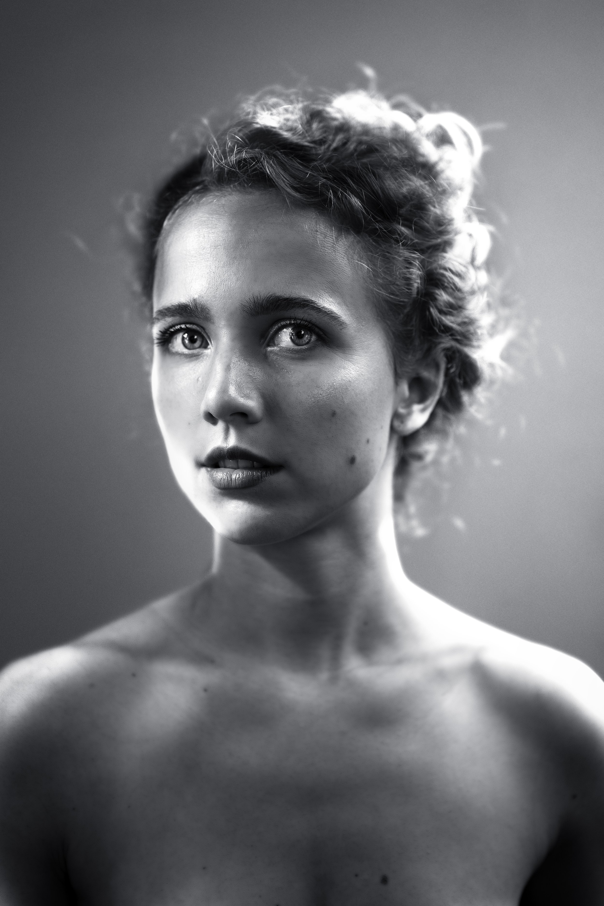 Black and white portrait of a young woman with curly hair, looking slightly to the side.