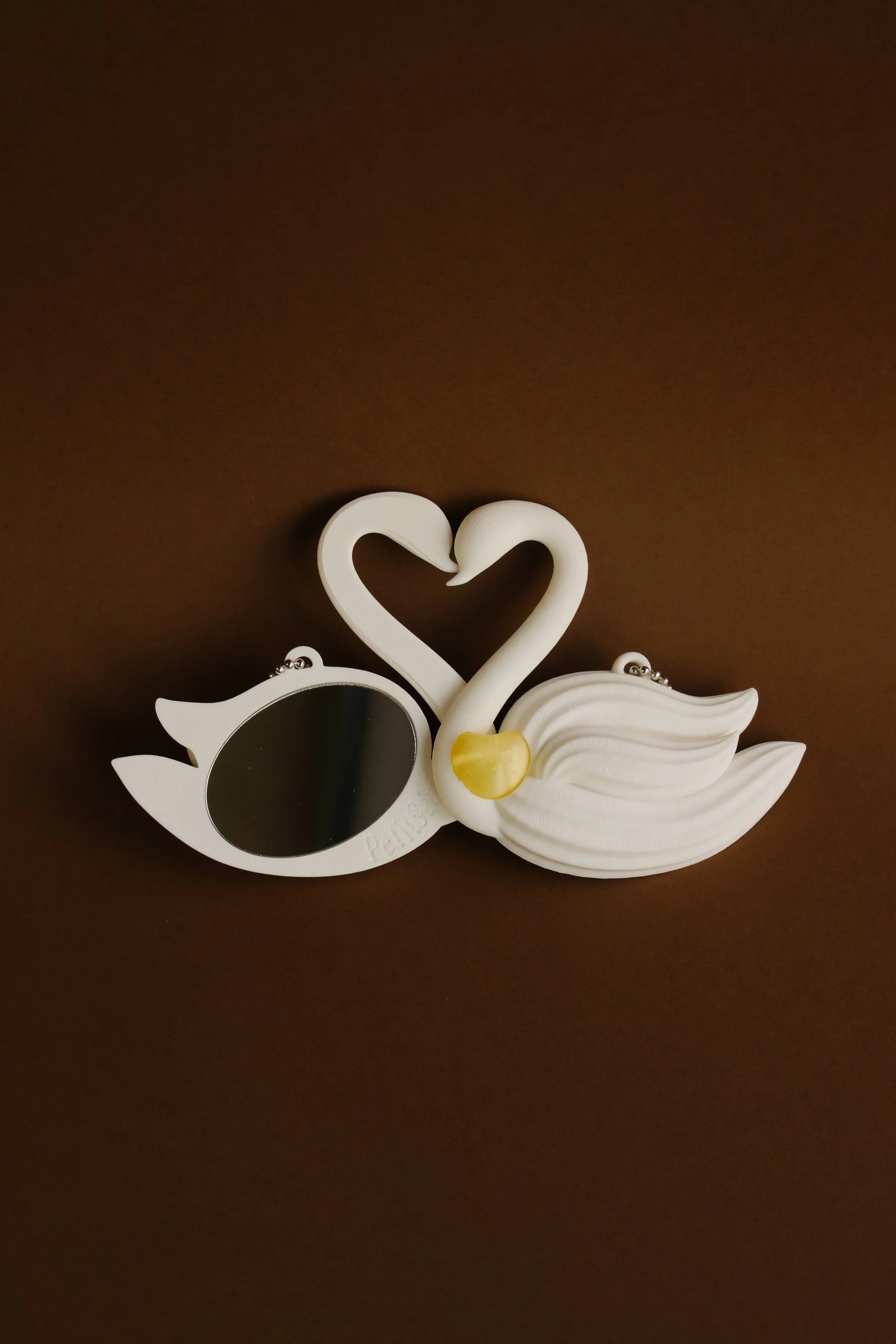 Decorative mirror with swan design and a heart-shaped neck, on a brown surface.