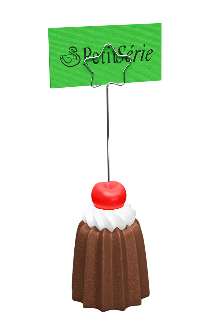 Decorative cake with a cherry and whipped cream, with a green sign that has a silver star-shaped wire on top and the words 'Petit Serie' in black letters.