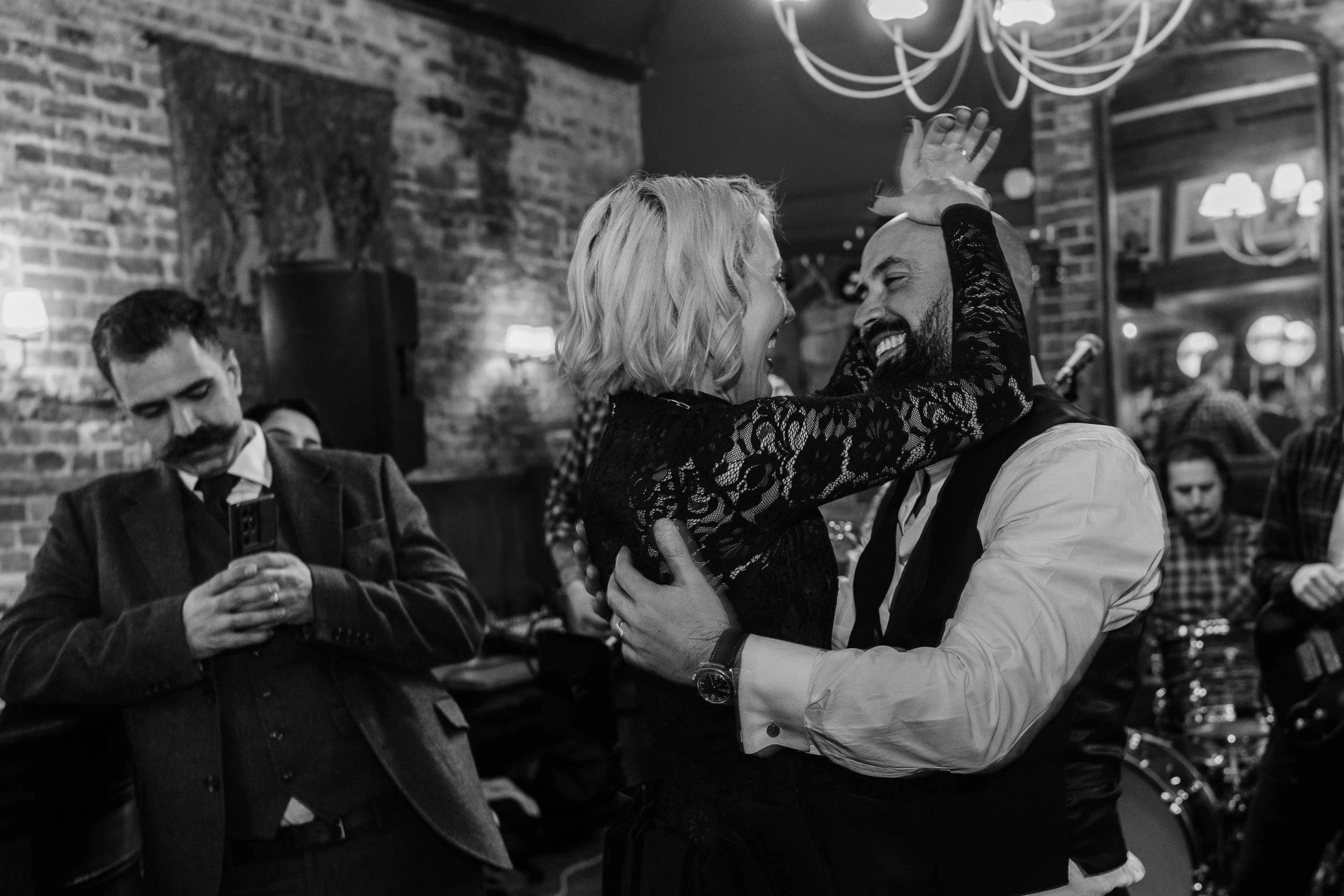 Bride and groom smiling and cuddling on the dance floor at the bar at a  wedding reception at The Bedford Arms in Chenies 