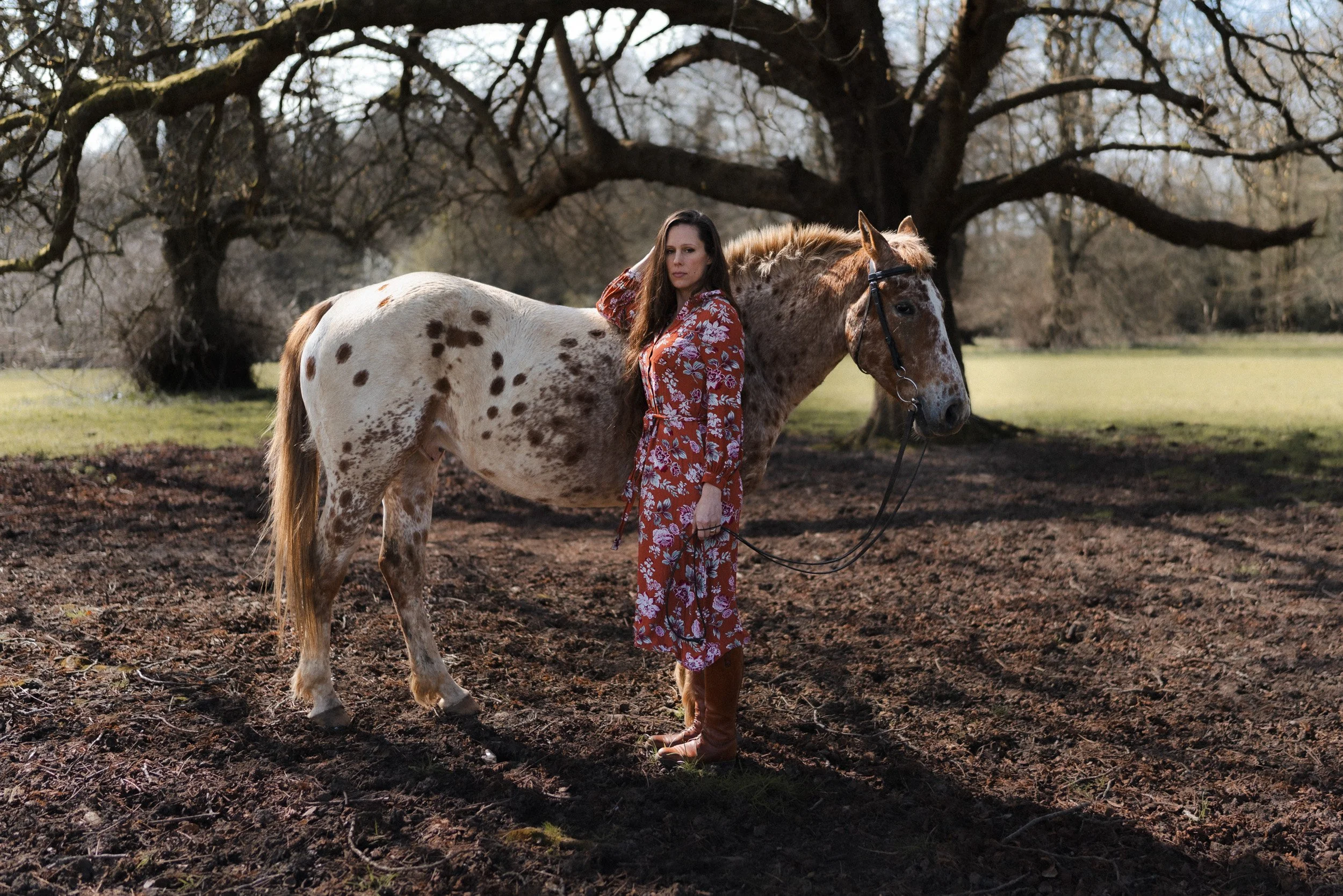 Equestrian fitness coach standing with Appaloosa polo pony in a paddock for a branding photoshoot at a polo club in Penn Buckinghamshire