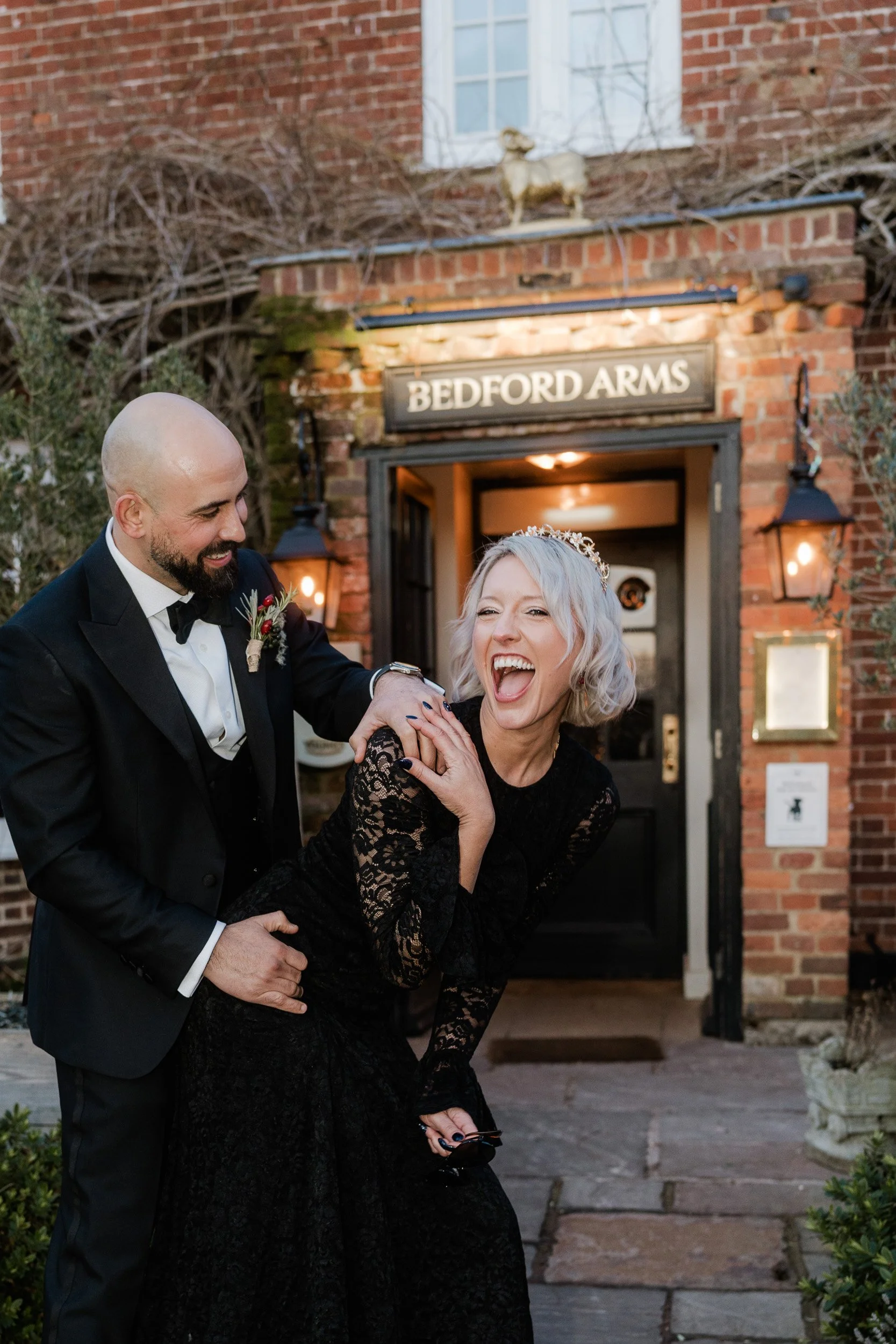 Bride and groom laughing together outside  The Bedford Arms in Chenies, Buckinghamshire during their wedding reception