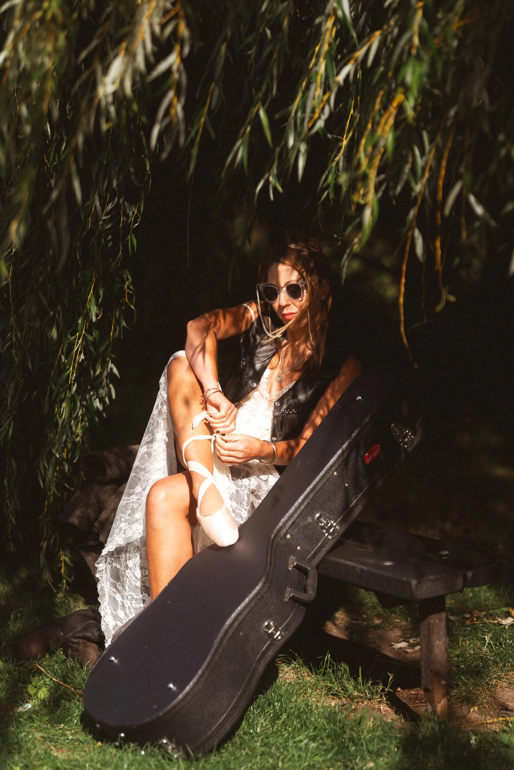 Musician personal branding portrait with guitar case under a willow tree in Windsor Berkshire