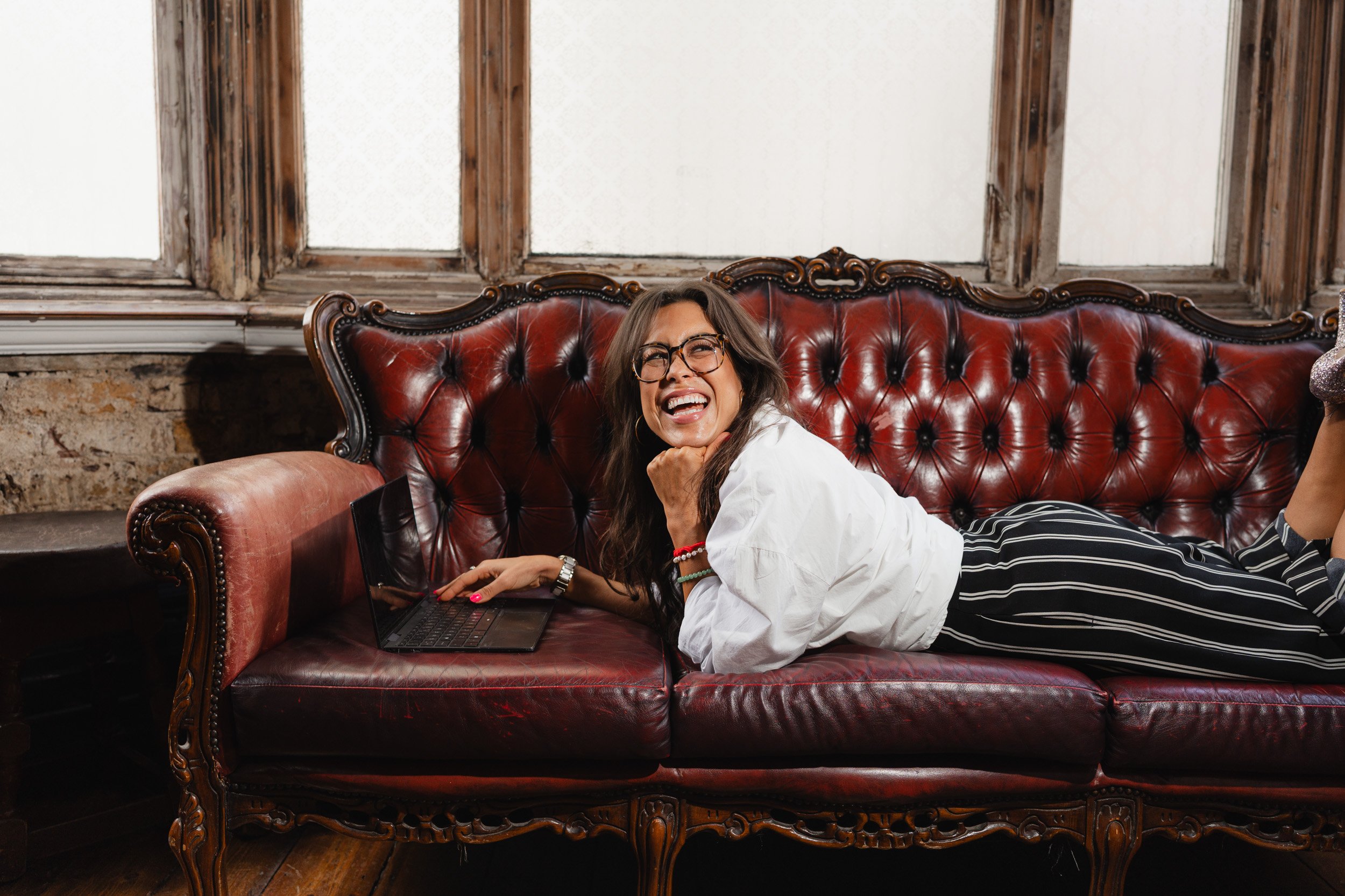 Female entrepreneur and life coach Alice Dartnell working on her laptop  during a personal branding photoshoot in London 