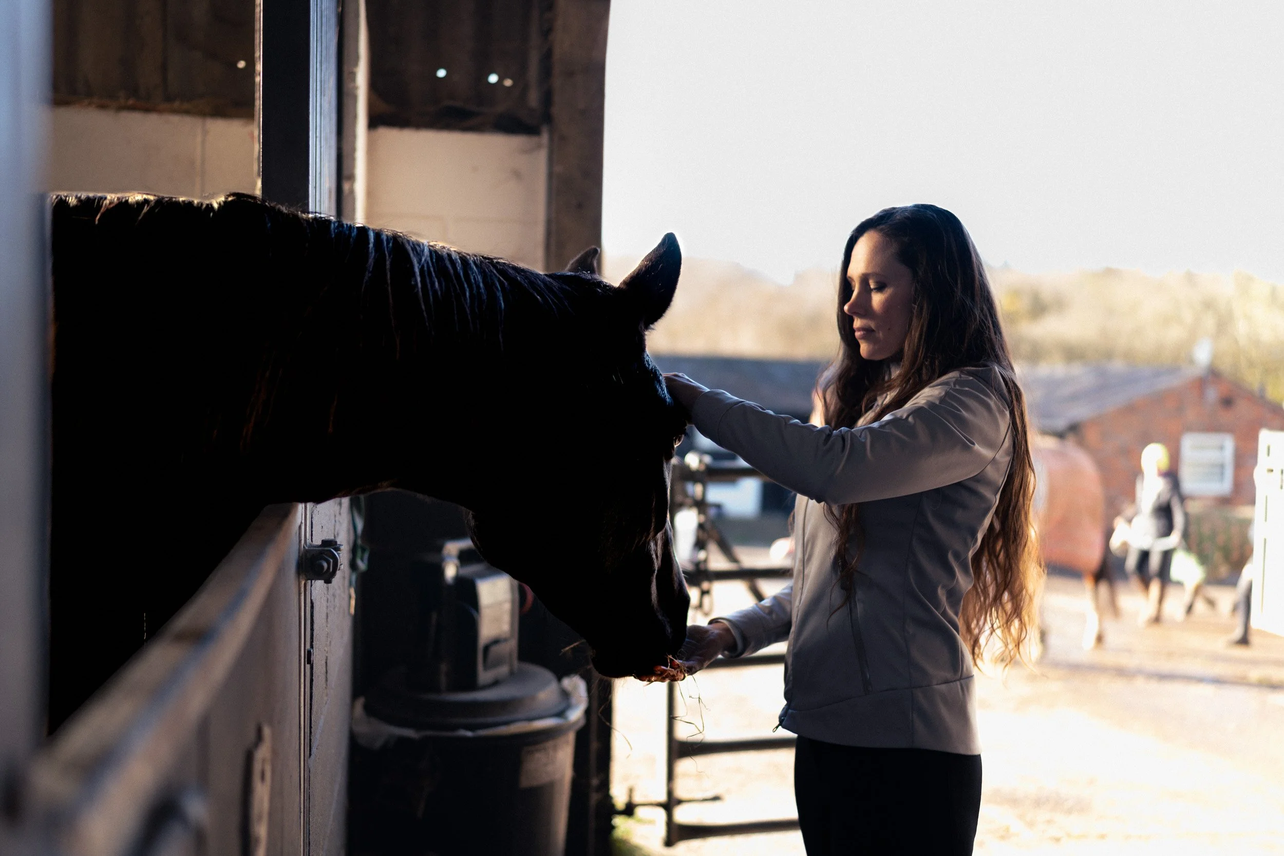 Equestrian fitness coach feeding her horse in the stables at Sean Hardy Horse Training in Great Missenden Buckinghamshire during a branding photoshoot
