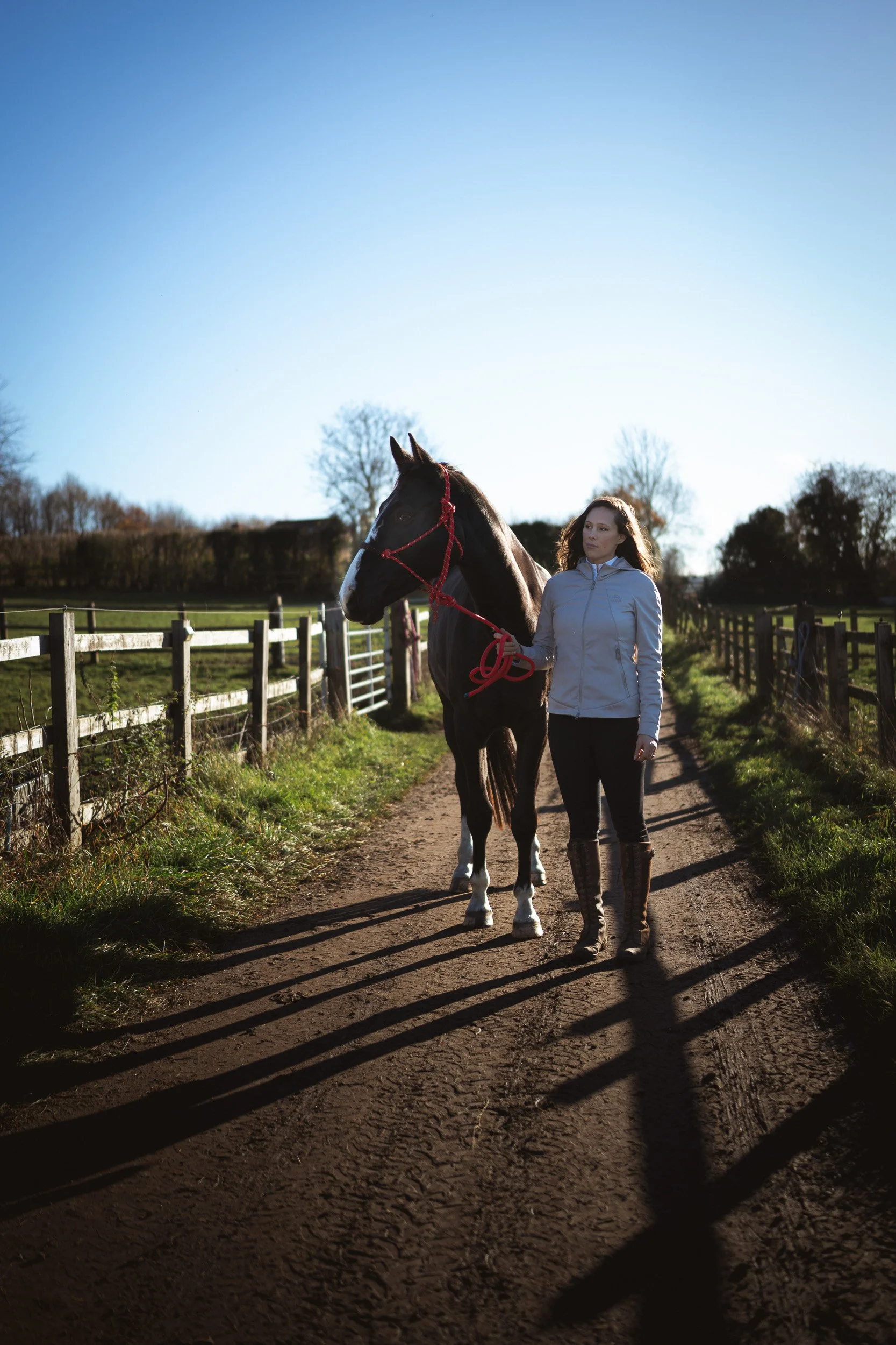 Equestrian fitness coach walking with her horse along a paddock track at Sean Hardy Horse Training in Great Missenden Buckinghamshire 