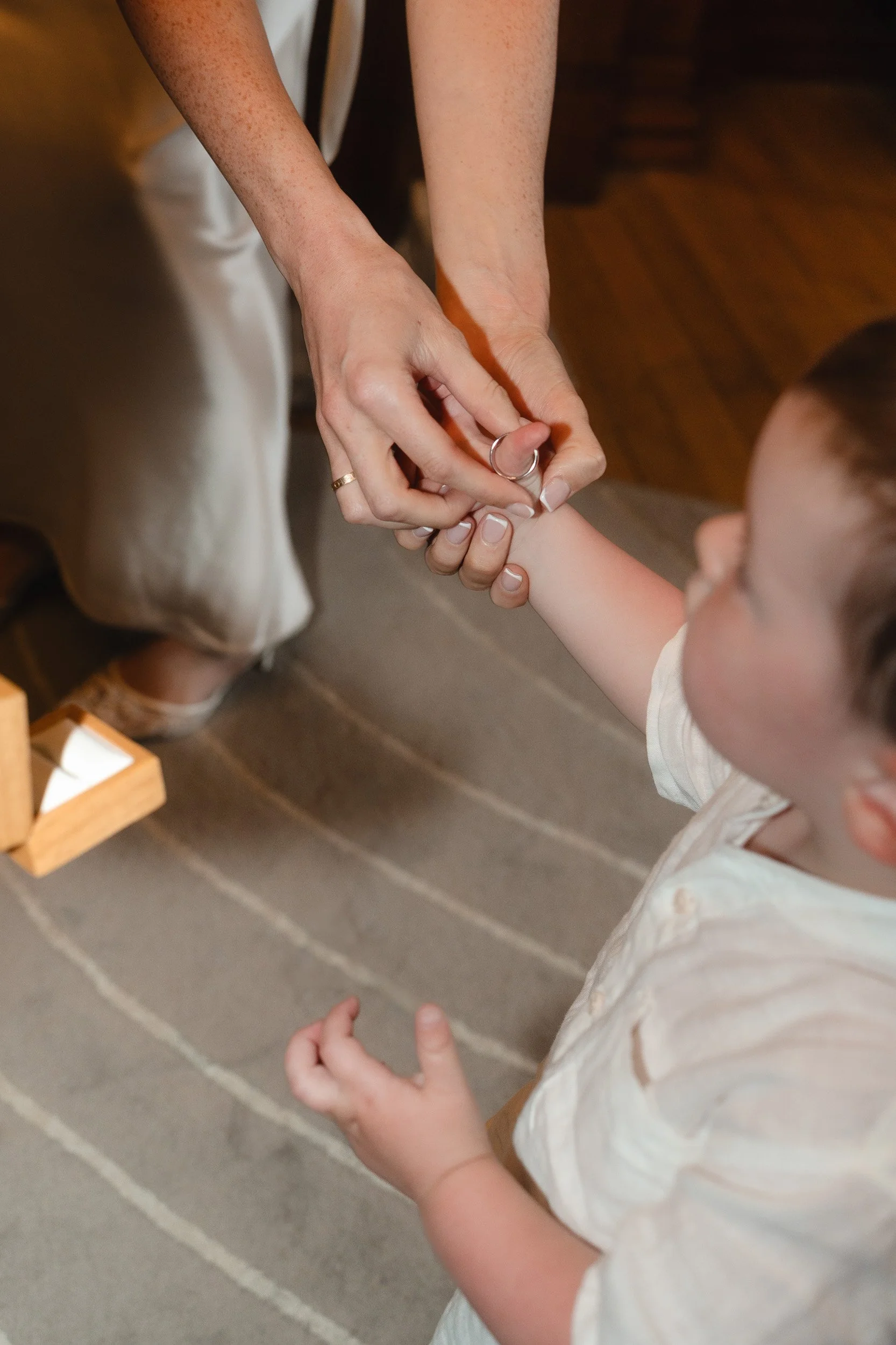 Bride takes her ring off her toddlers thumb  at  her small wedding ceremony at Marylebone Town Hall Registry Office in London  