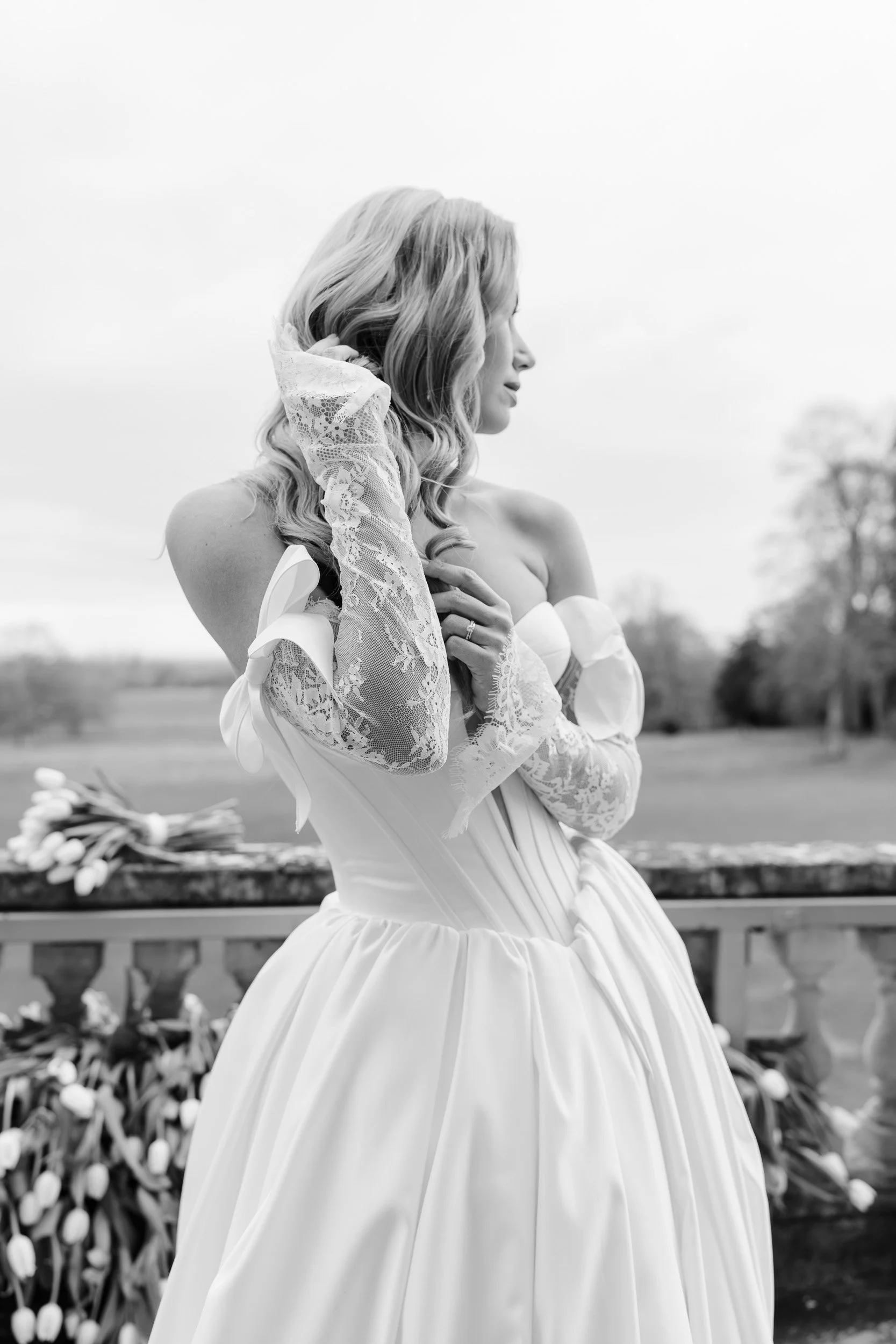 Close-up of the Bride on a tulip-lined balcony wearing lace gloves at Kirtlington Park in Oxfordshire