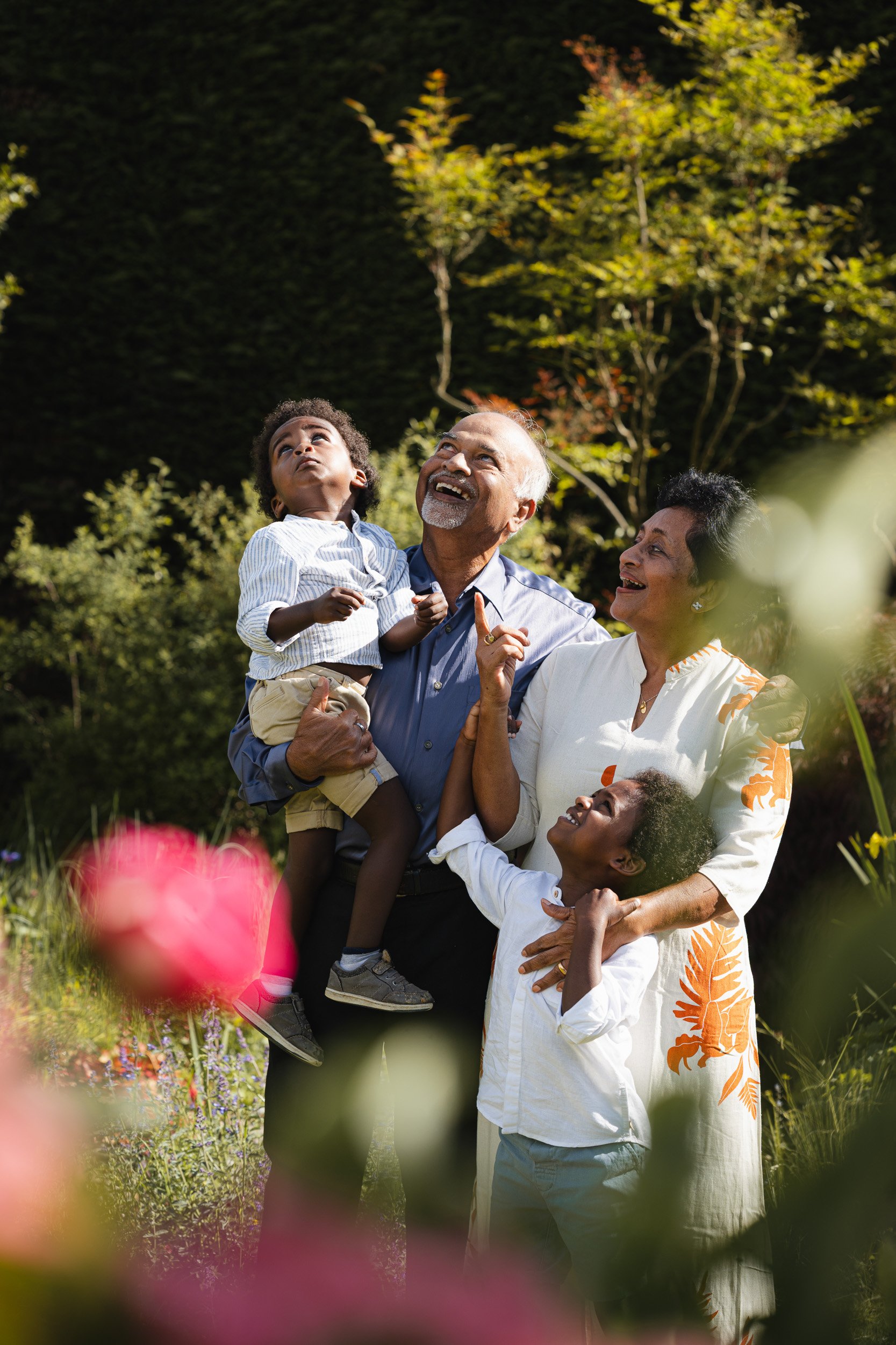 Grandparent cuddling their grandchildren among the garden flowers during an at-home family photo session in Buckinghamshire