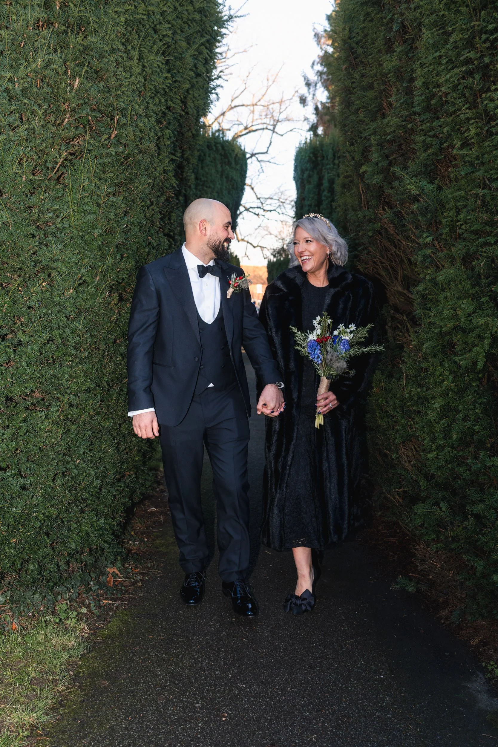 Bride and groom walking through the grounds of the the church in Old Beaconsfield Buckinghamshire before their wedding ceremony