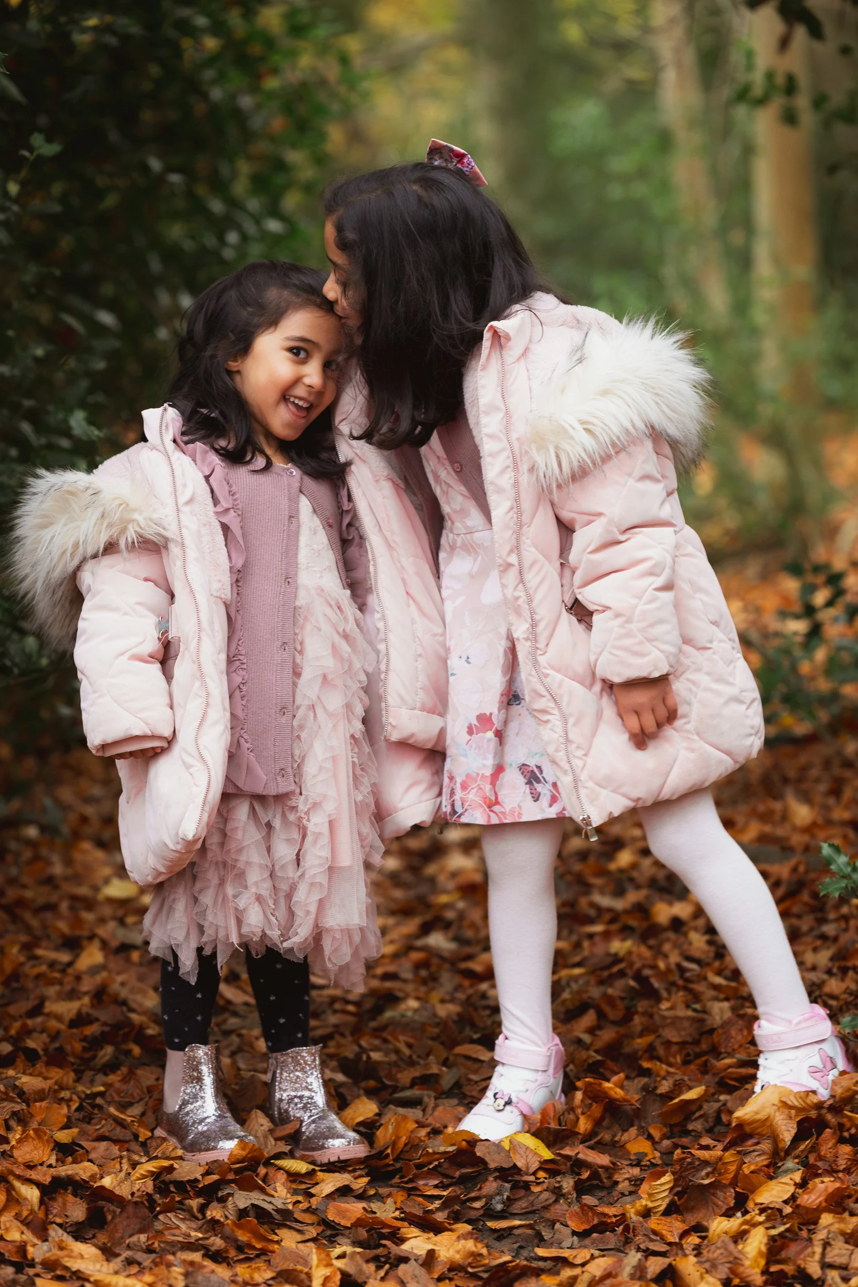 Two young sisters sharing a moment together among  autumn leaves during a natural outdoor family photography session in the countryside near Thame, Oxfordshire