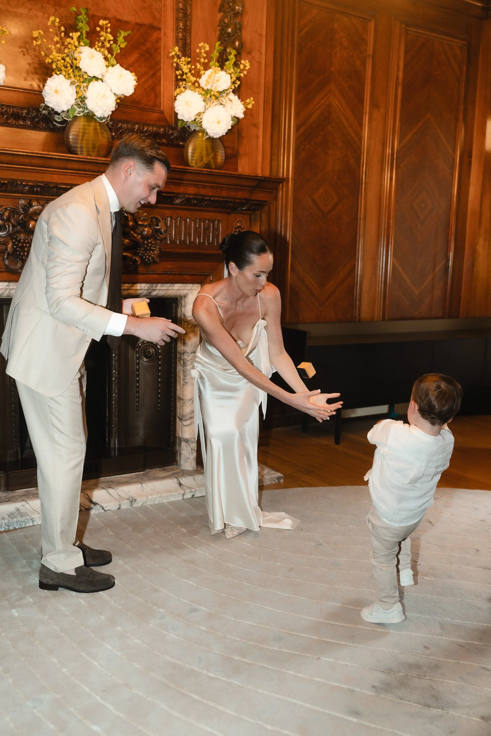 Bride and groom laughing as their toddler throws the wedding ring box at  their intimate wedding ceremony at Marylebone Town Hall Registry Office in London  