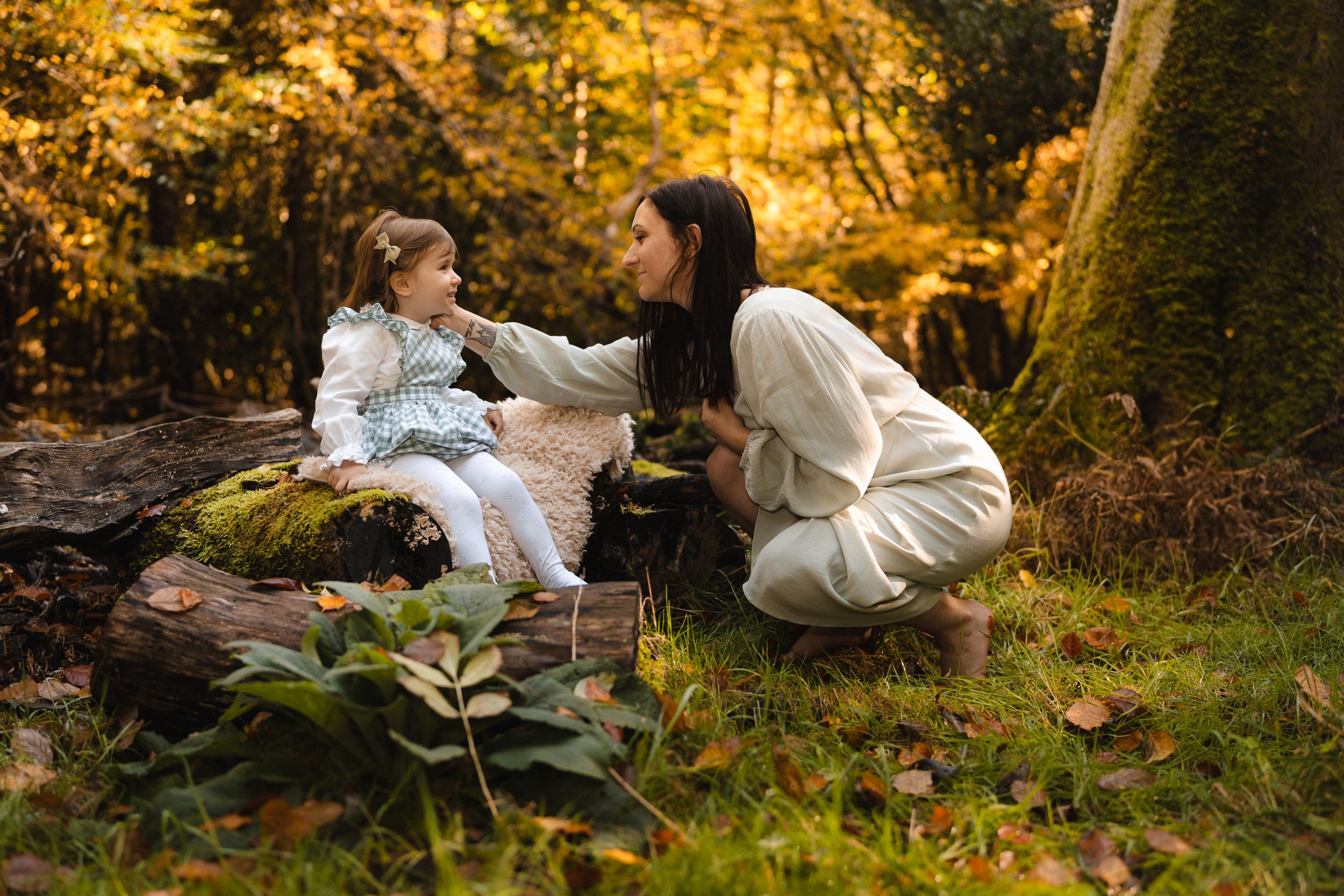 Mother reaching to touch her toddler face in peaceful woodland motherhood photography session in woods in Amersham, Buckinghamshire 