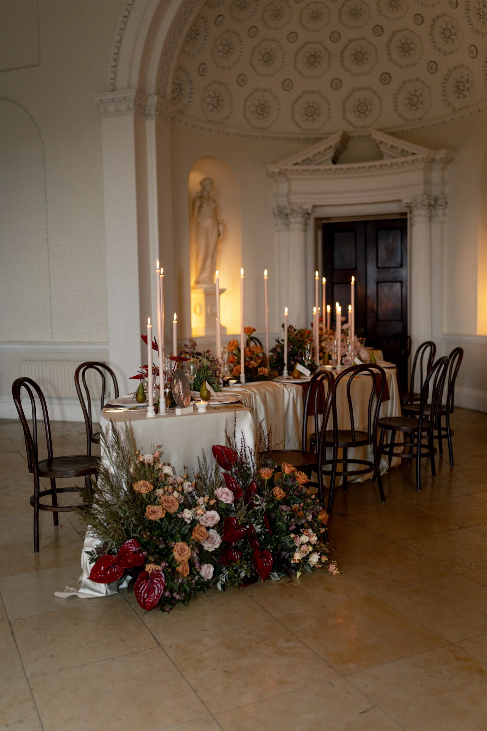 Head table at a wedding reception at Kirtlington Park in Oxfordshire featuring soft pink florals and candles and romantic lighting 