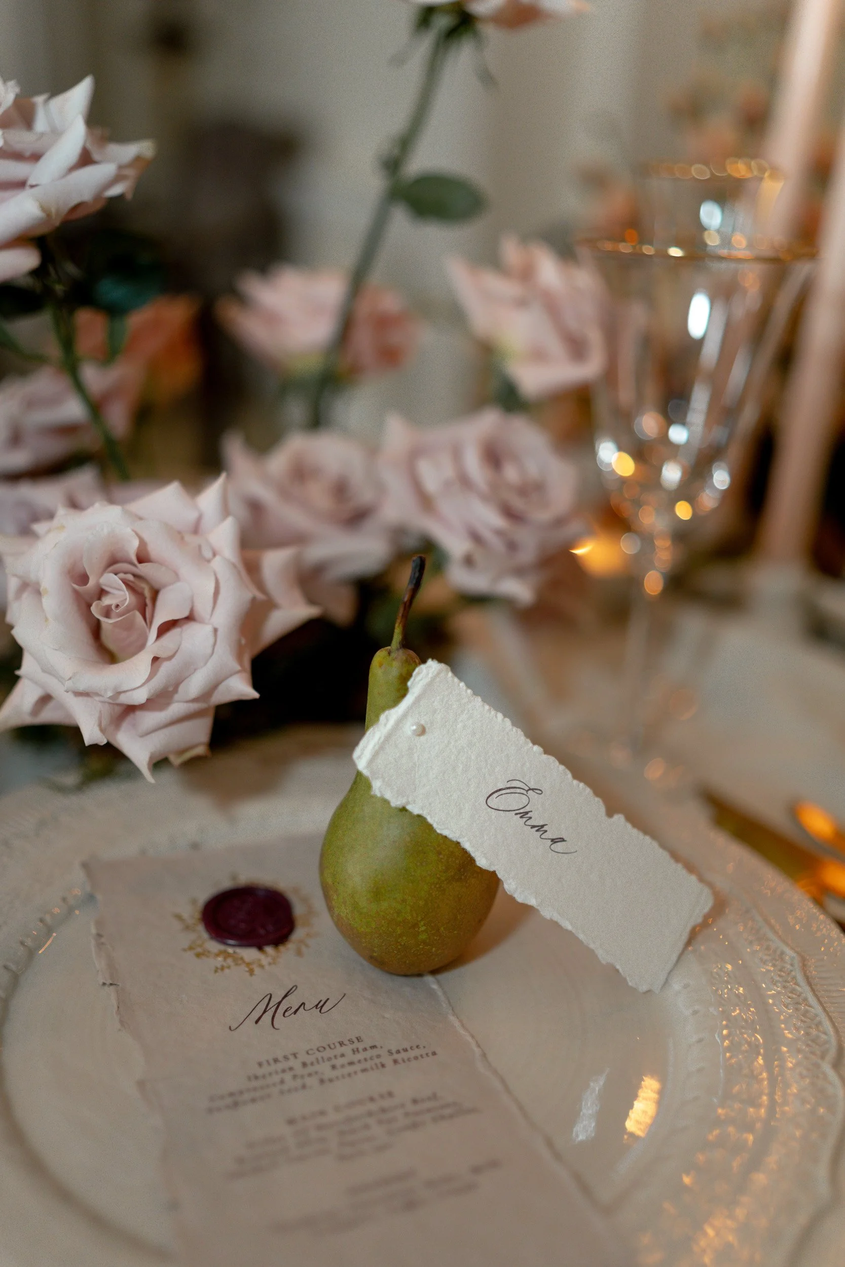 Wedding reception table with florals and a pear name tag place setting at Kirtlington Park in Oxfordshire