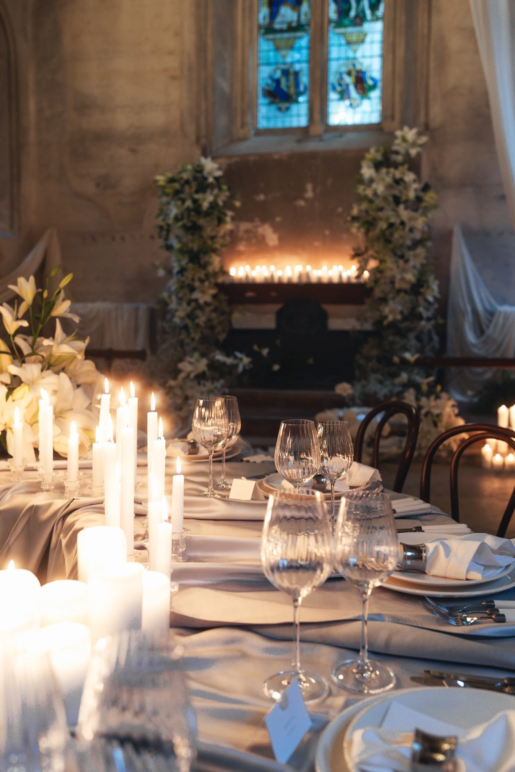 A close up of a  candlelit reception room with flowing drapery and long banquet tables inside The Bell Tower at The Elvetham Hotel in Hampshire