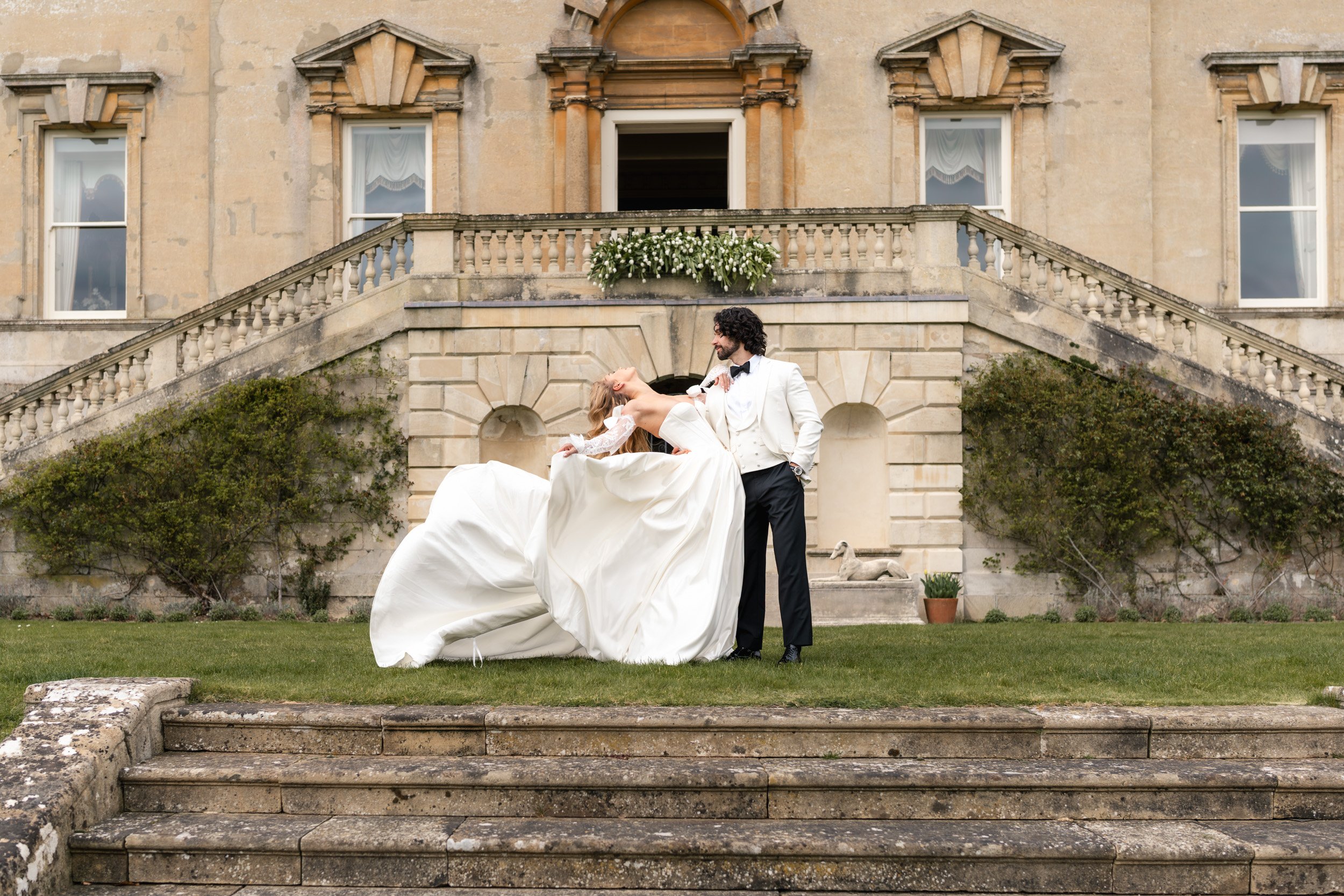 Groom dipping his bride for a kiss on the lawn outside Kirtlington Park in Oxfordshire