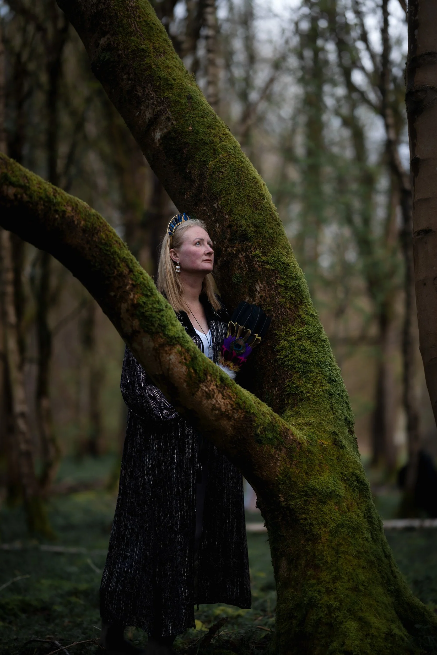 Sound healer and yoga instructor standing beneath moss covered trees during a wellness photoshoot in Amersham woods in Buckinghamshire