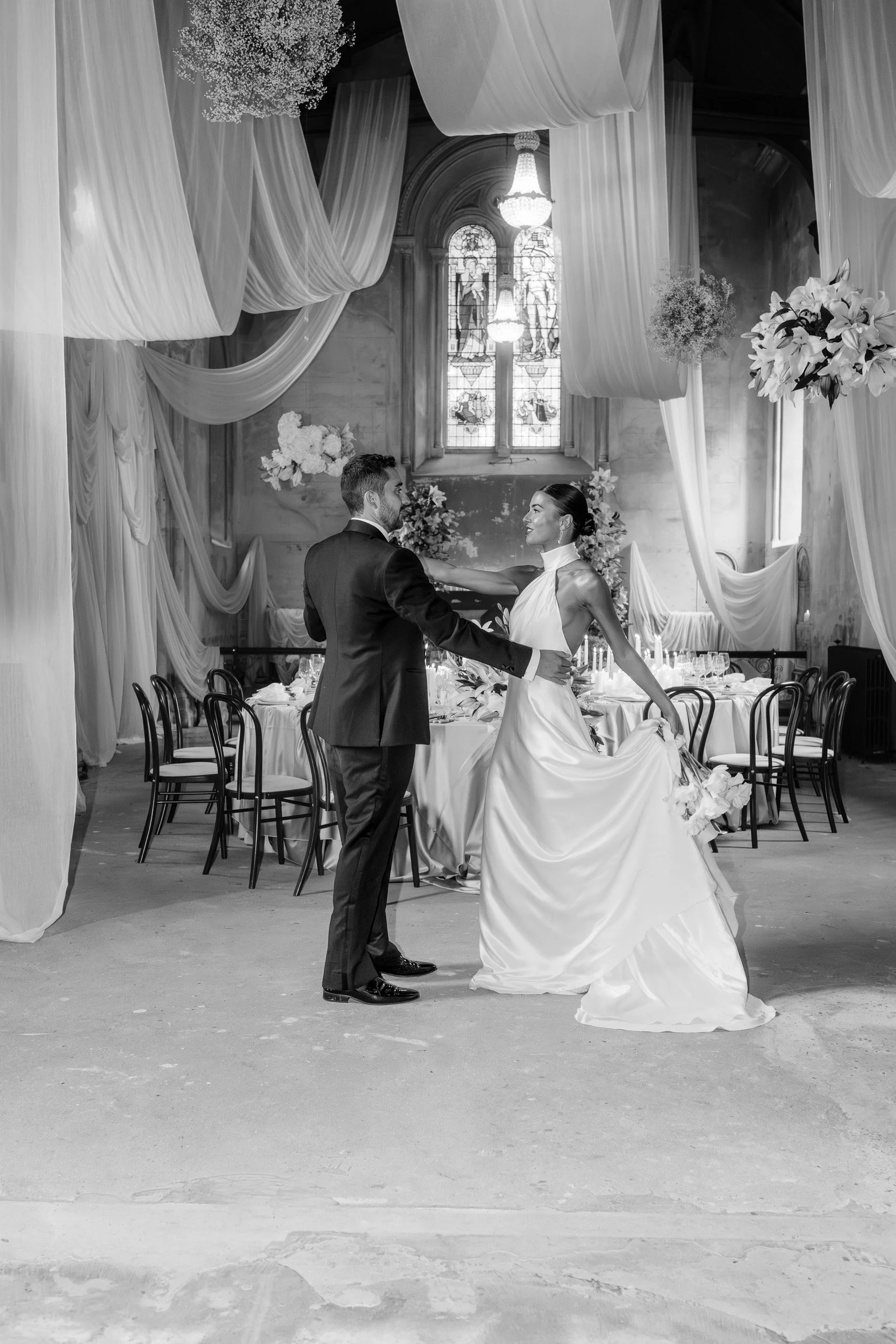 Bride and groom dancing during their candlelit reception in a  room with draped fabric and floral displays inside The Bell Tower at The Elvetham Hotel in Hampshire