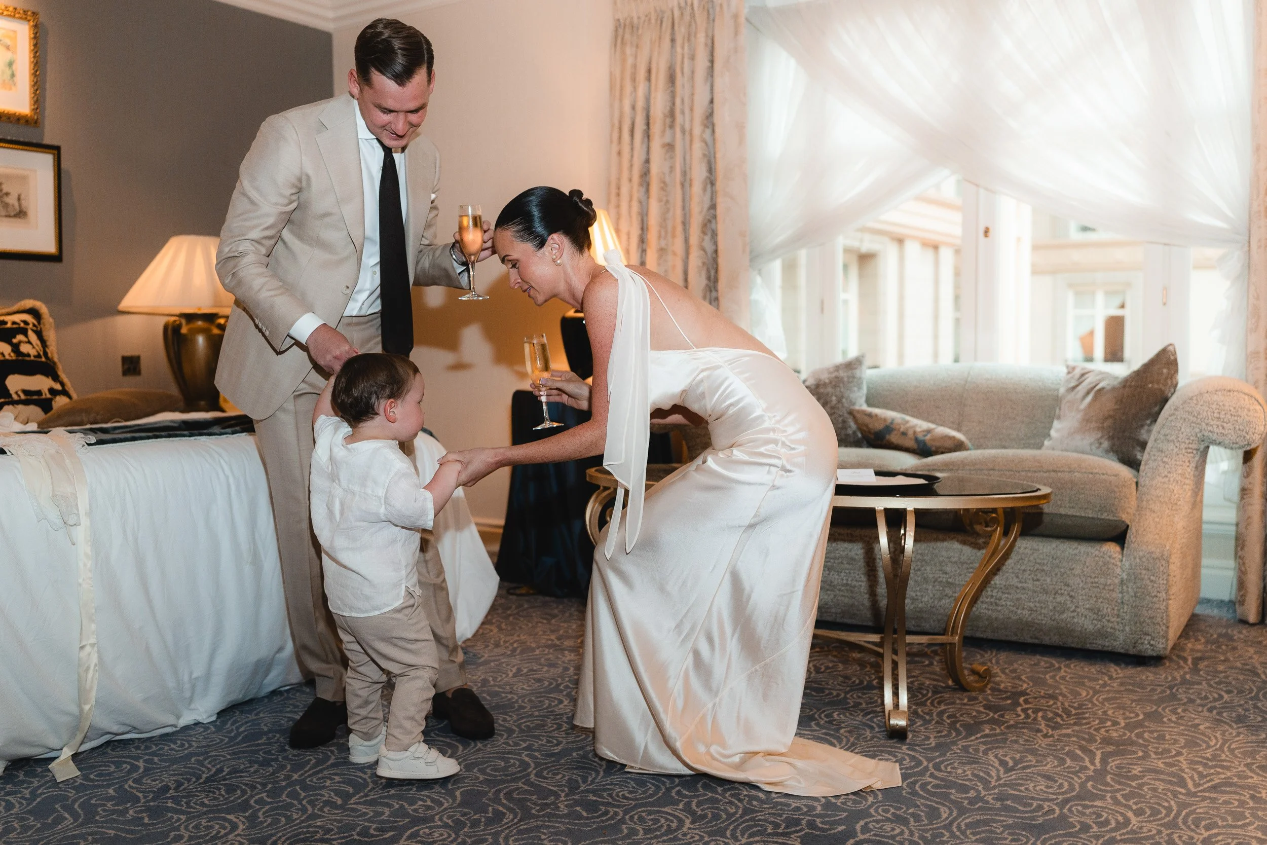 Bride and groom doting on their toddler in a suite at The Landmark Hotel in London