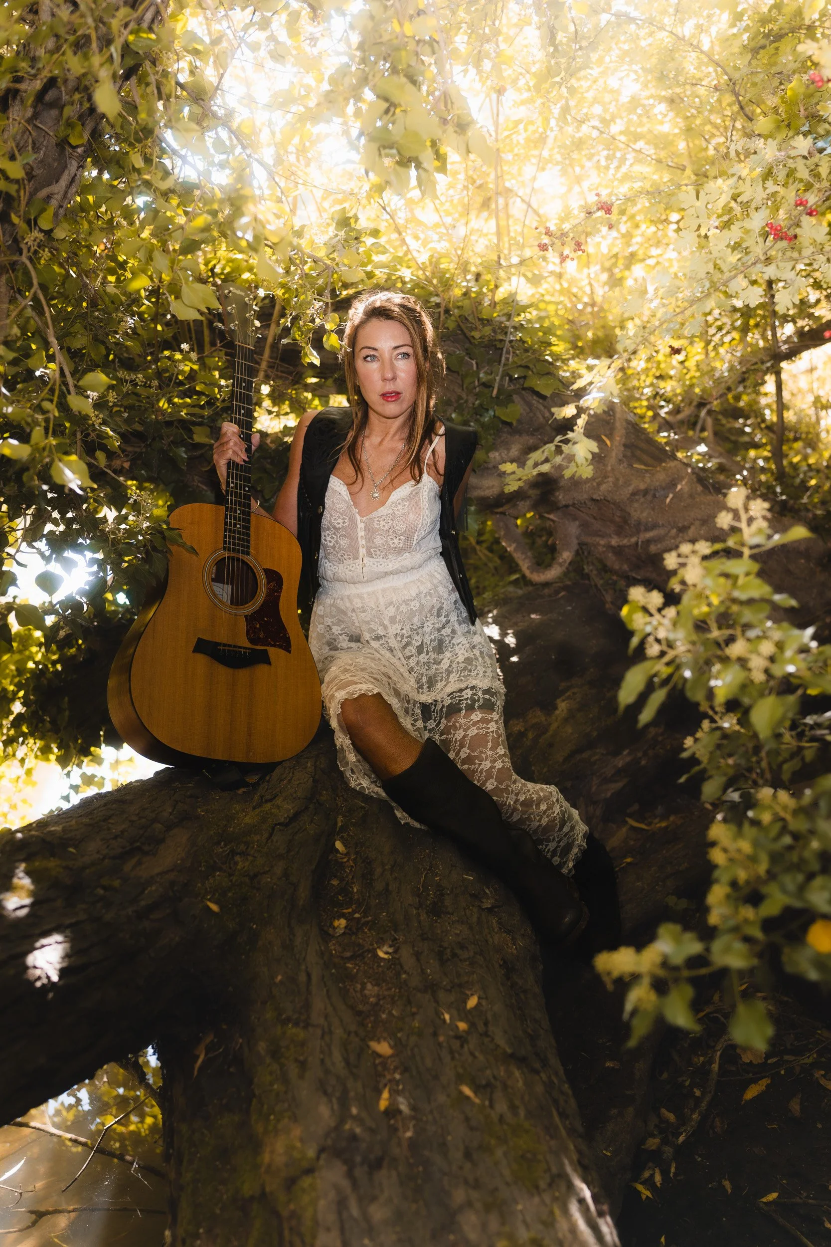 Musician branding portrait with acoustic guitar sitting on tree trunk  in Windsor Berkshire