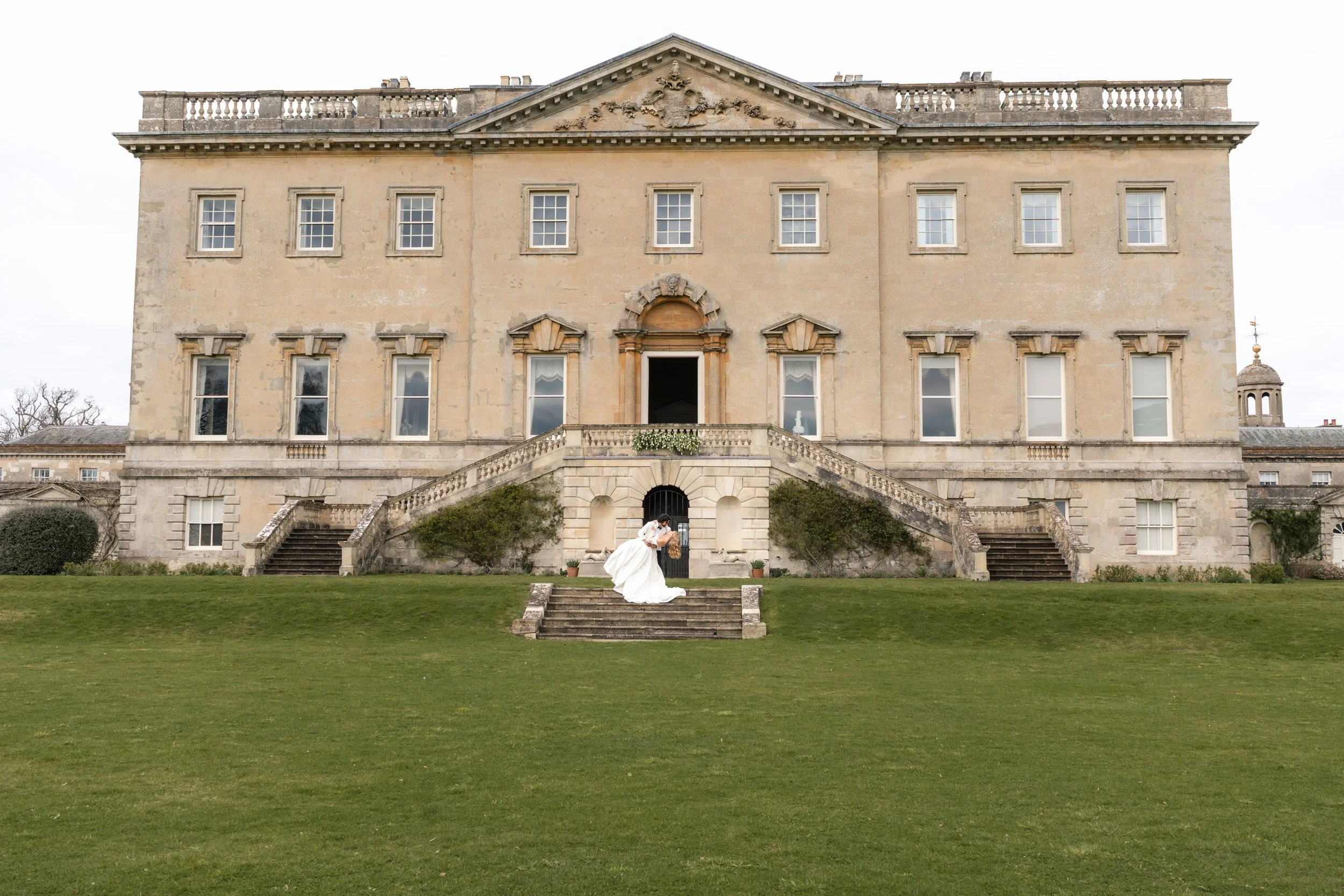 Groom dipping his bride for a kiss on the lawn outside Kirtlington Park in Oxfordshire