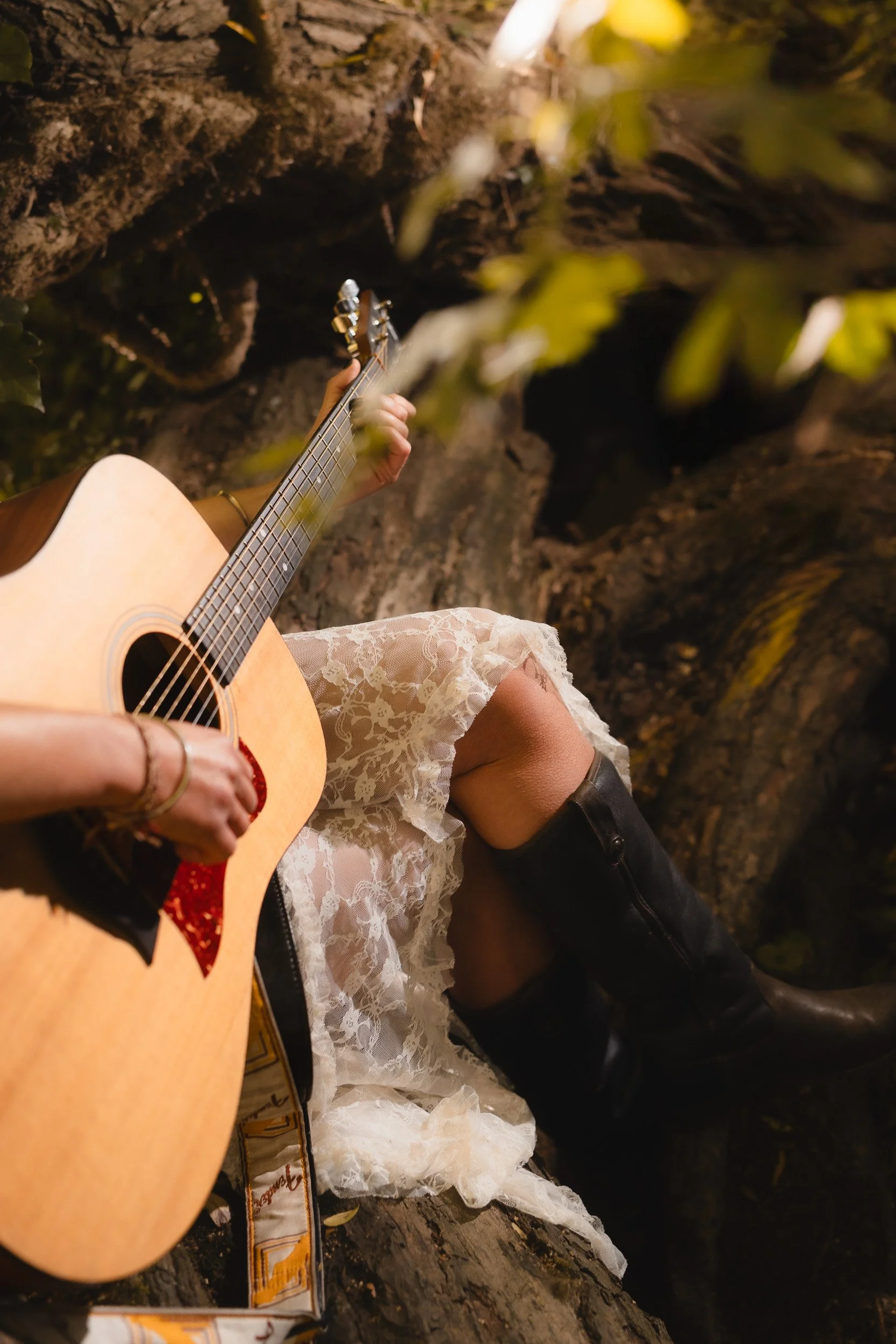 Branding portrait close up of a musician playing the guitar with her cowboy boots on the amp among the trees the park in Windsor Berkshire