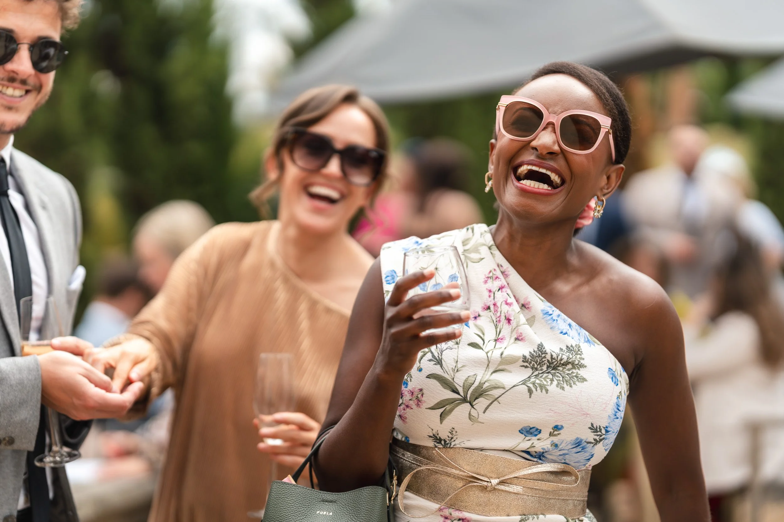 Wedding guests laughing in the gardens during the drinks reception at Wasing Park in Berkshire