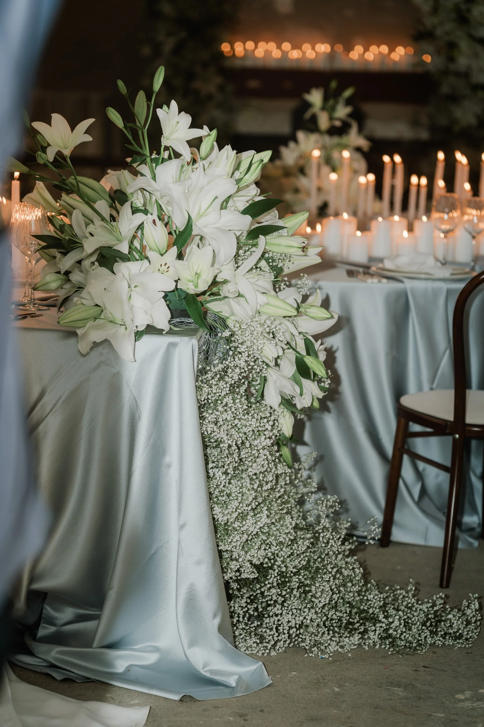 Elegant candlelit wedding reception table with white floral arrangements and draped linens at The Bell Tower at The Elvetham Hotel in Hampshire